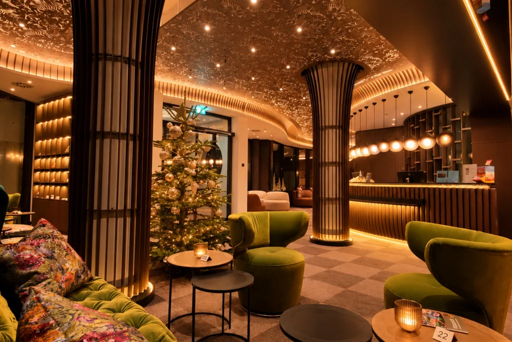 Für Feiern in kleiner und großer Runde Hotel-Lounge mit grünen Samtsesseln, dekoriertem Weihnachtsbaum und kunstvoll beleuchteter Decke