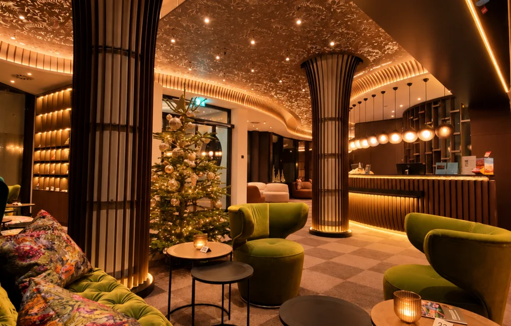 Für Feiern in kleiner und großer Runde Hotel-Lounge mit grünen Samtsesseln, dekoriertem Weihnachtsbaum und kunstvoll beleuchteter Decke