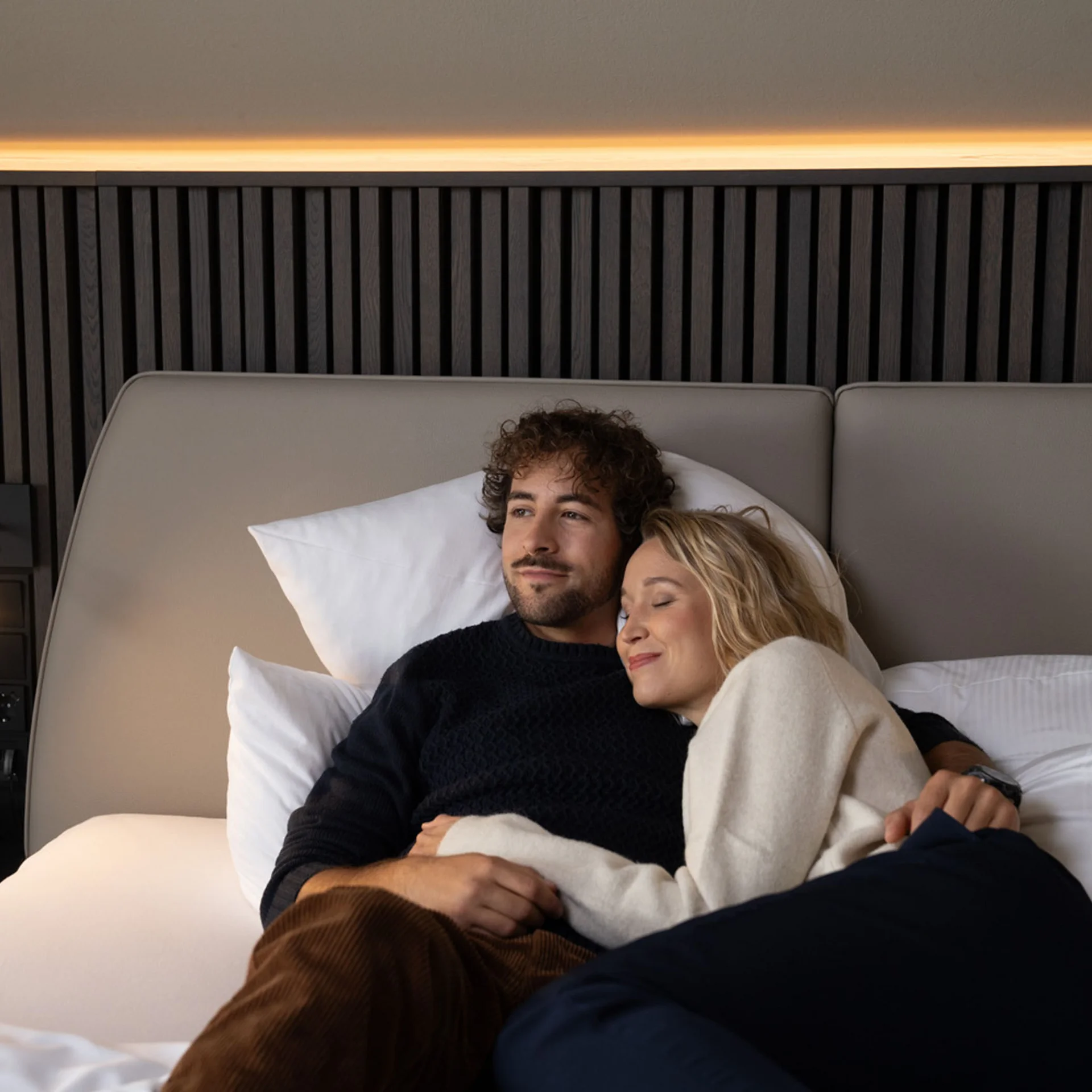 Paar liegt entspannt auf einem Bett in modernem Schlafzimmer