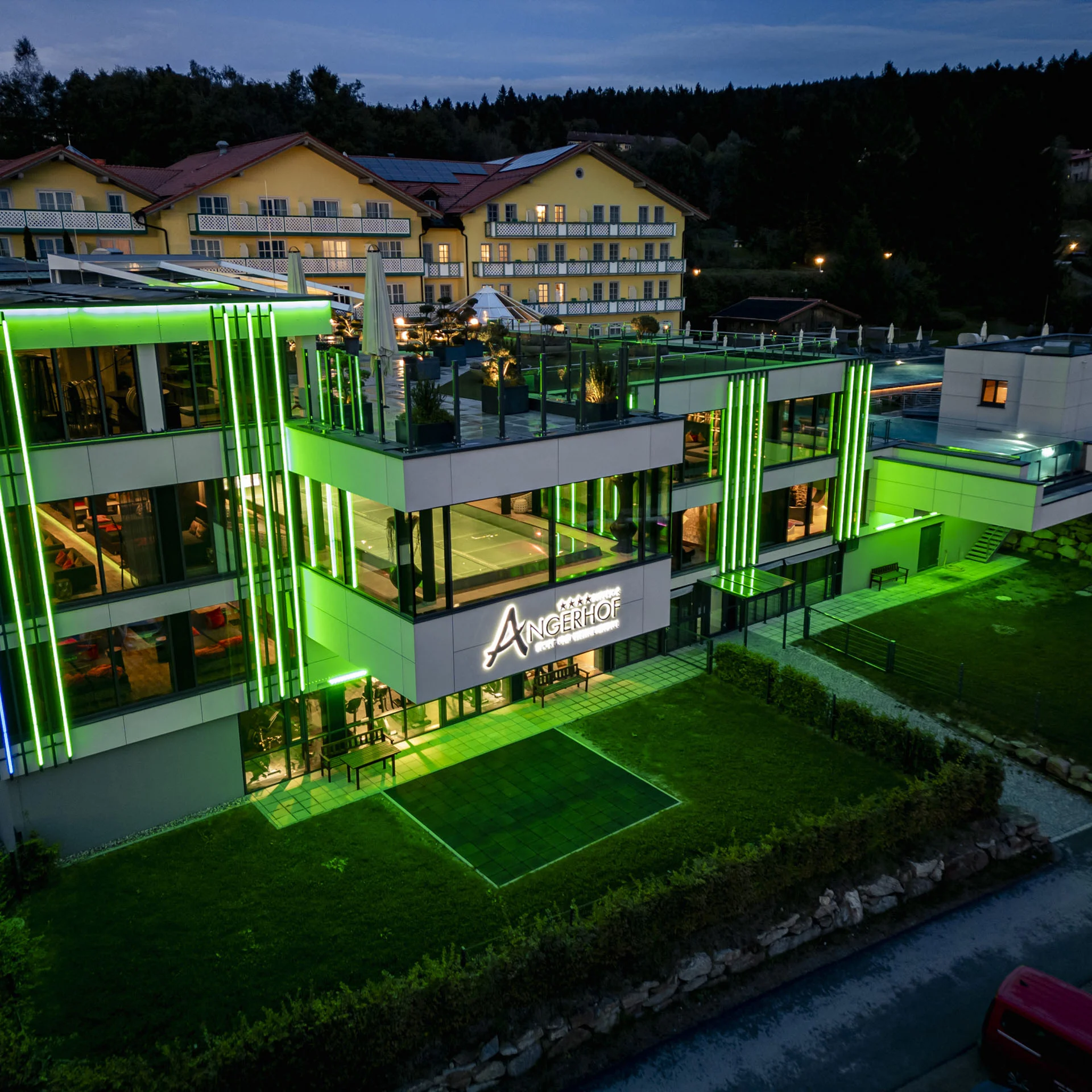 Modernes Hotel Angerhof bei Nacht mit grüner Außenbeleuchtung
