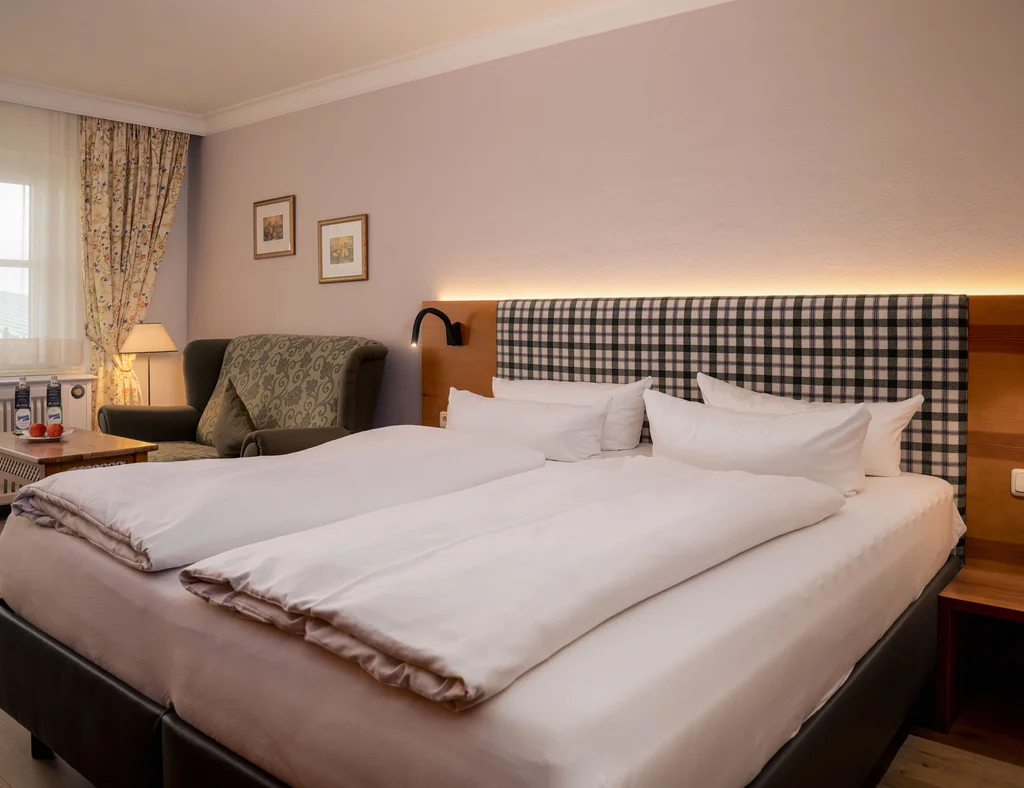 Komfortables Hotelzimmer mit Doppelbett, Sessel und Tageslicht durch Fenster