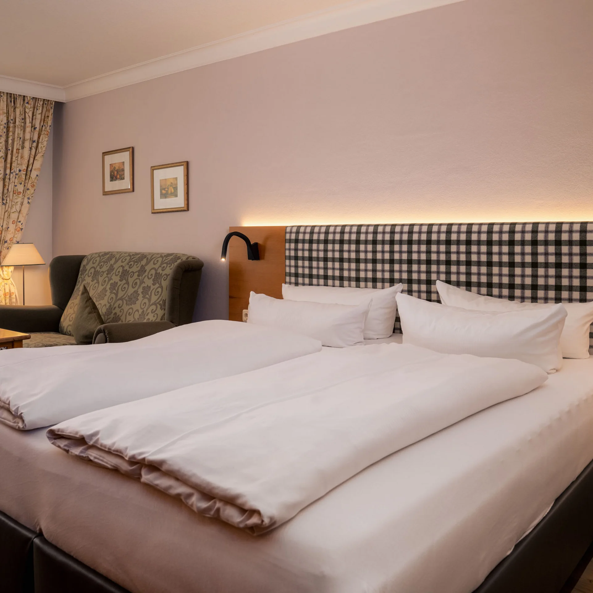 Komfortables Hotelzimmer mit Doppelbett, Sessel und Tageslicht durch Fenster