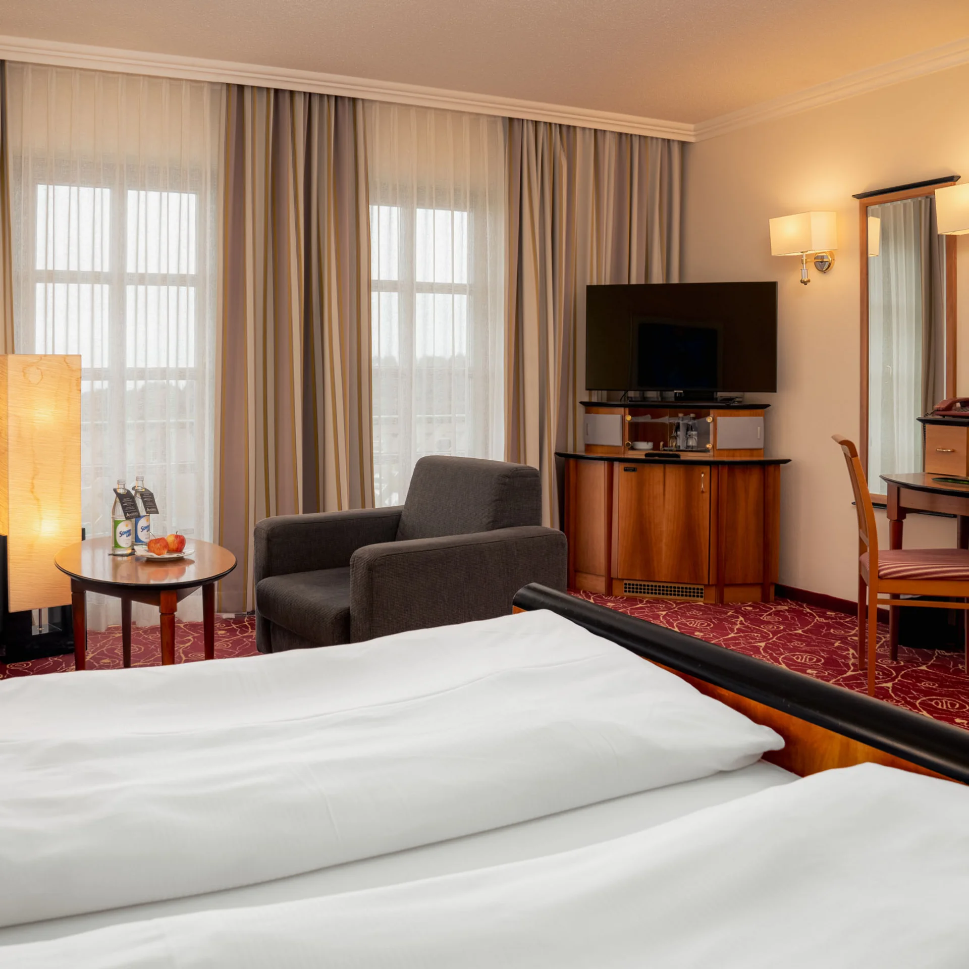 Gemütliches Hotelzimmer mit Bett, Sesseln, Fernseher und Schminktisch