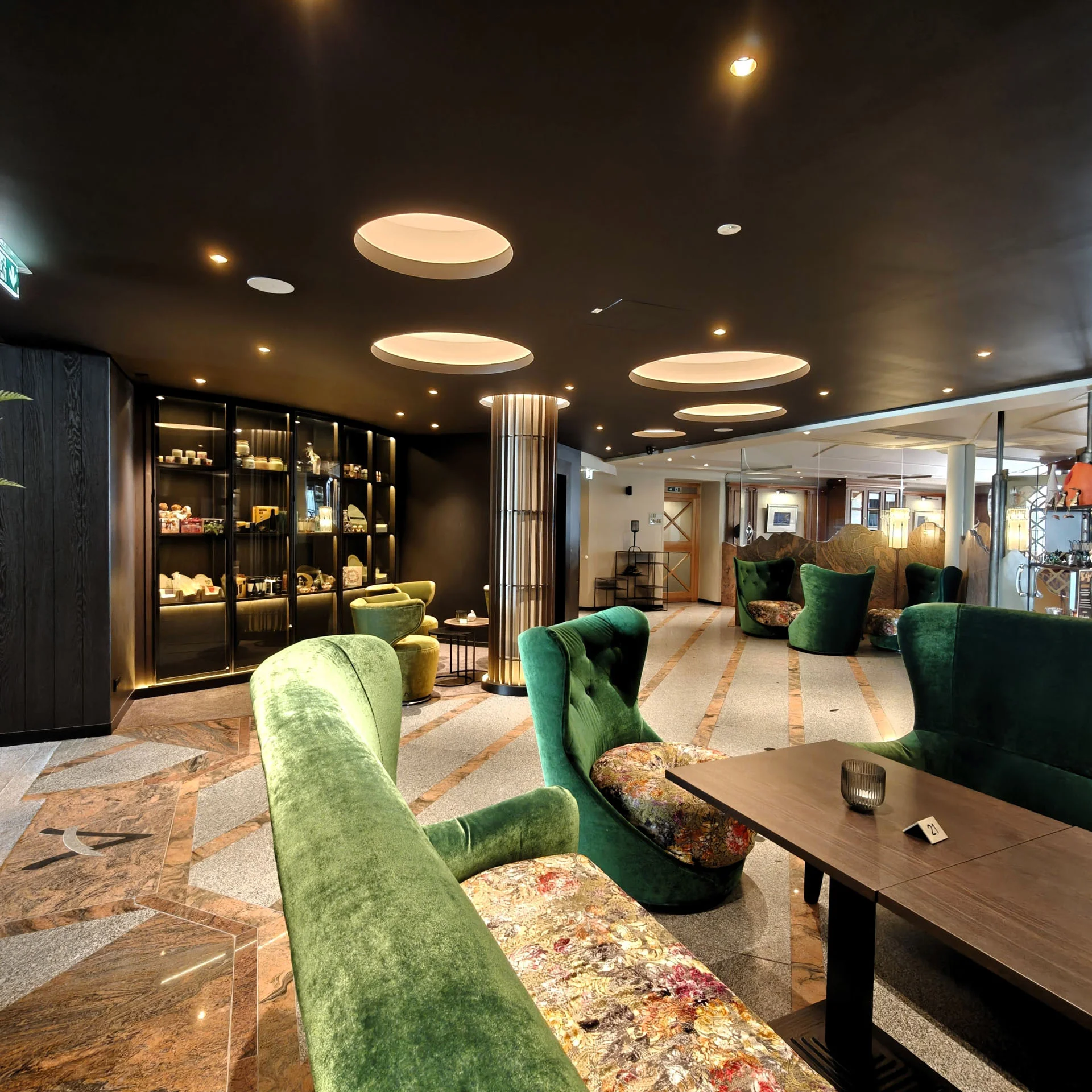Moderner Lounge-Bereich mit grünen Sesseln und dunklem Deckenlicht