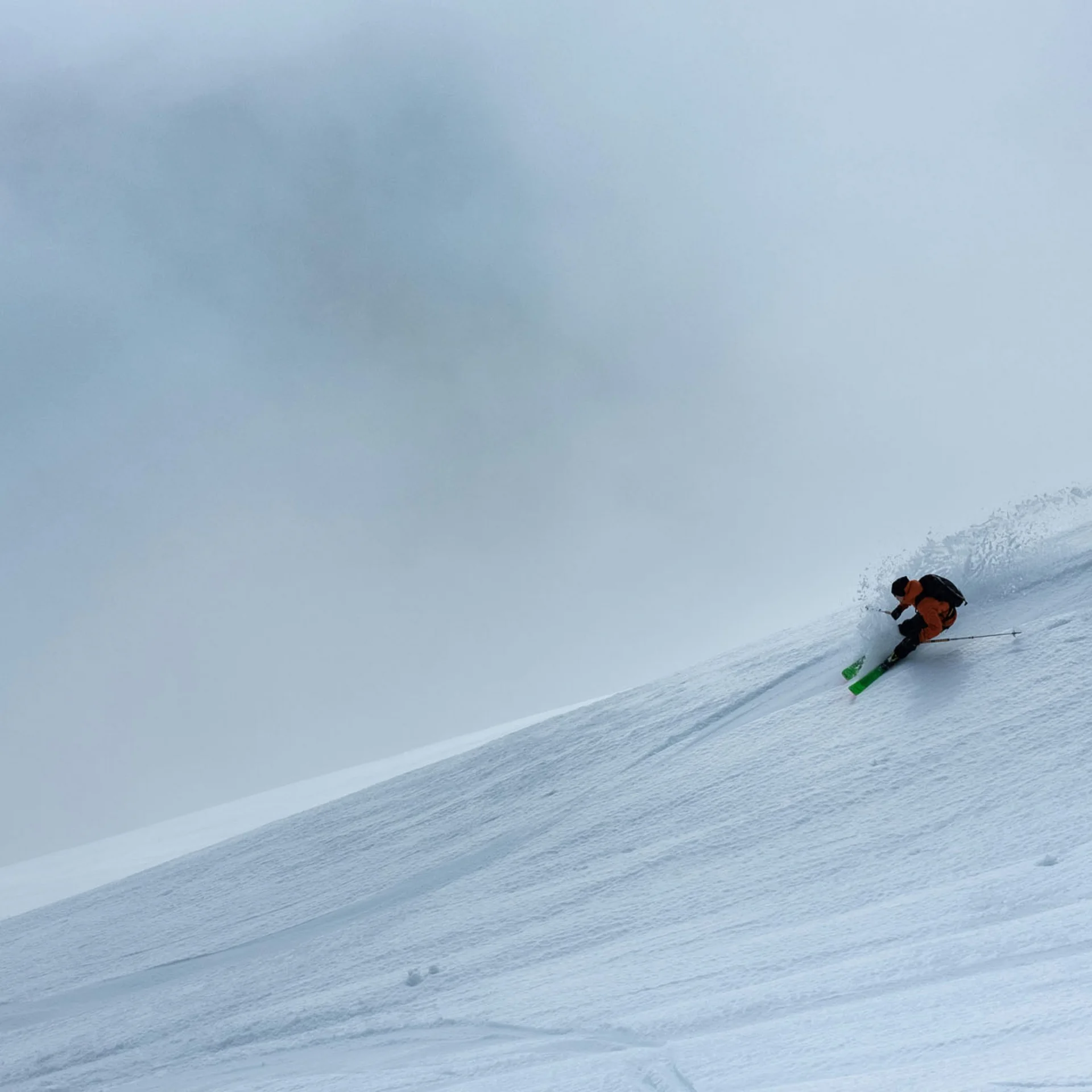 Skifahrer fährt einen steilen, verschneiten Hang mit leichter Wolkenbedeckung hinab