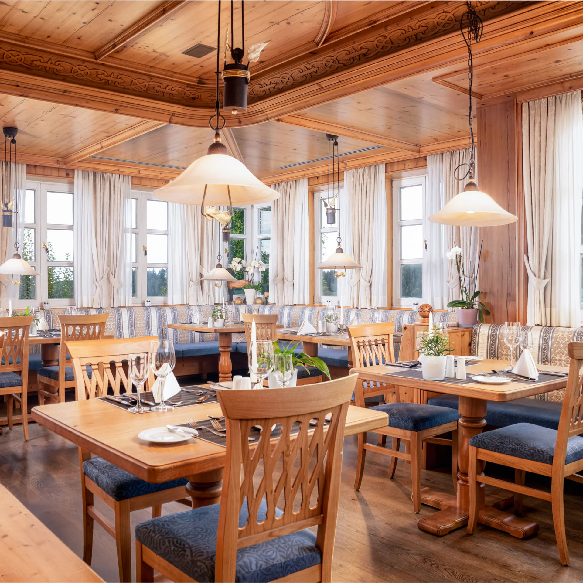Gemütliches Holzrestaurant mit gedeckten Tischen und großen Fenstern