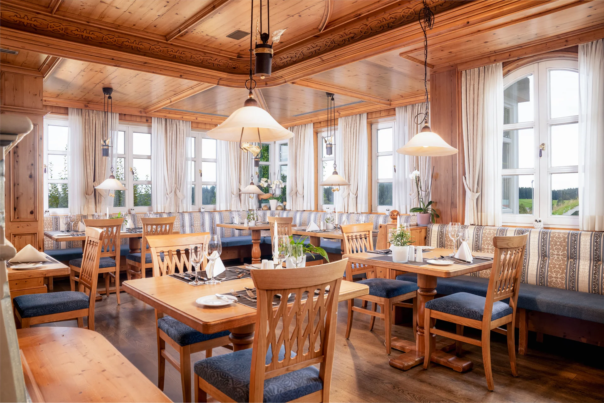 Gemütliches Holzrestaurant mit gedeckten Tischen und großen Fenstern
