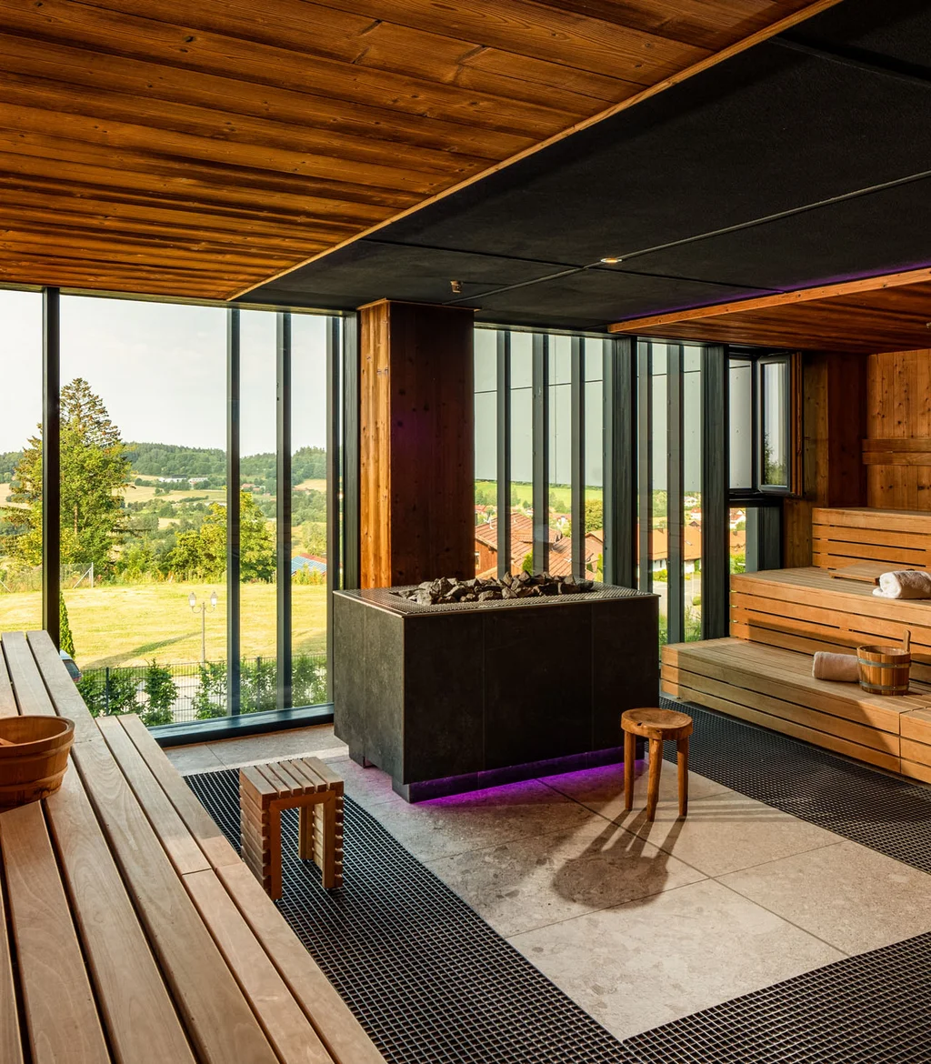 Moderne Sauna mit Holzvertäfelung und Panoramafenster mit Aussicht auf grüne Landschaft