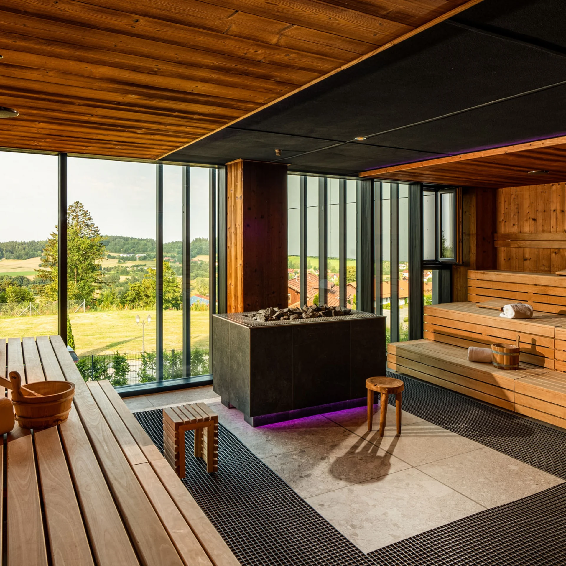 Moderne Sauna mit Holzvertäfelung und Panoramafenster mit Aussicht auf grüne Landschaft