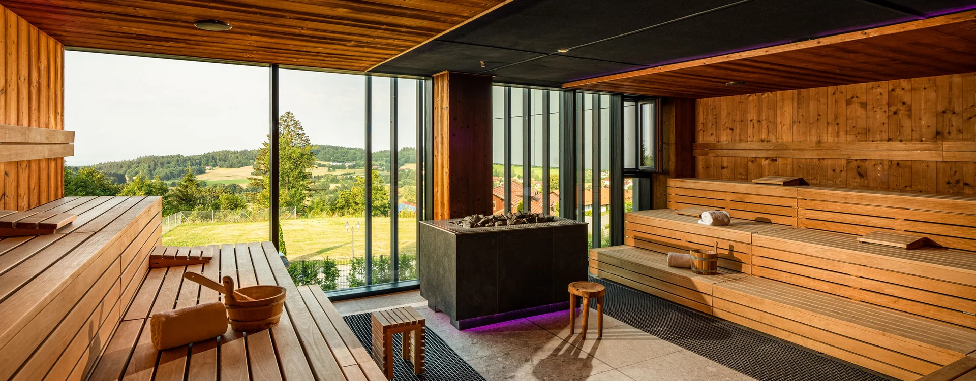 Moderne Sauna mit Holzvertäfelung und Panoramafenster mit Aussicht auf grüne Landschaft