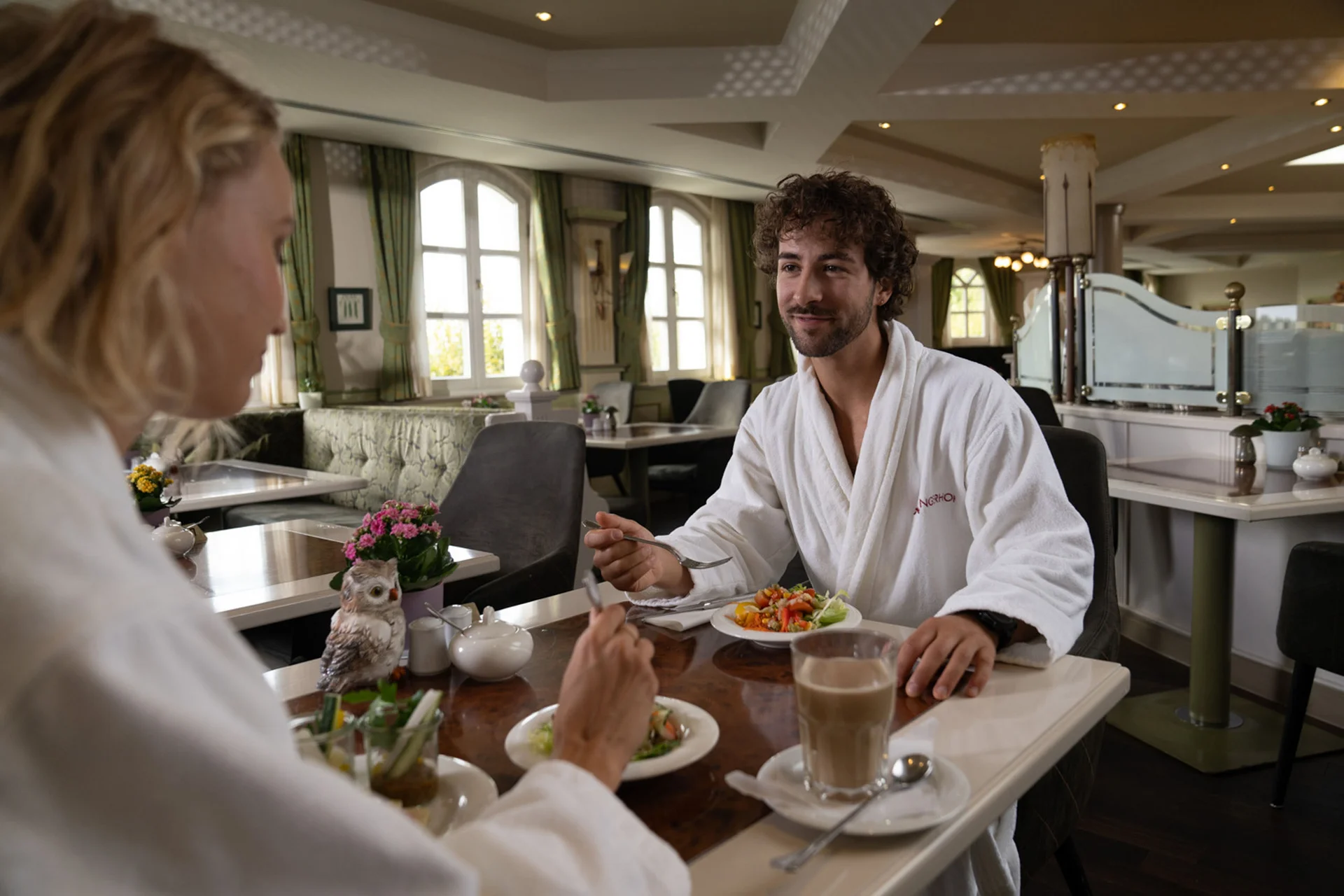 Zwei Personen essen Salat im Restaurant und tragen Bademäntel