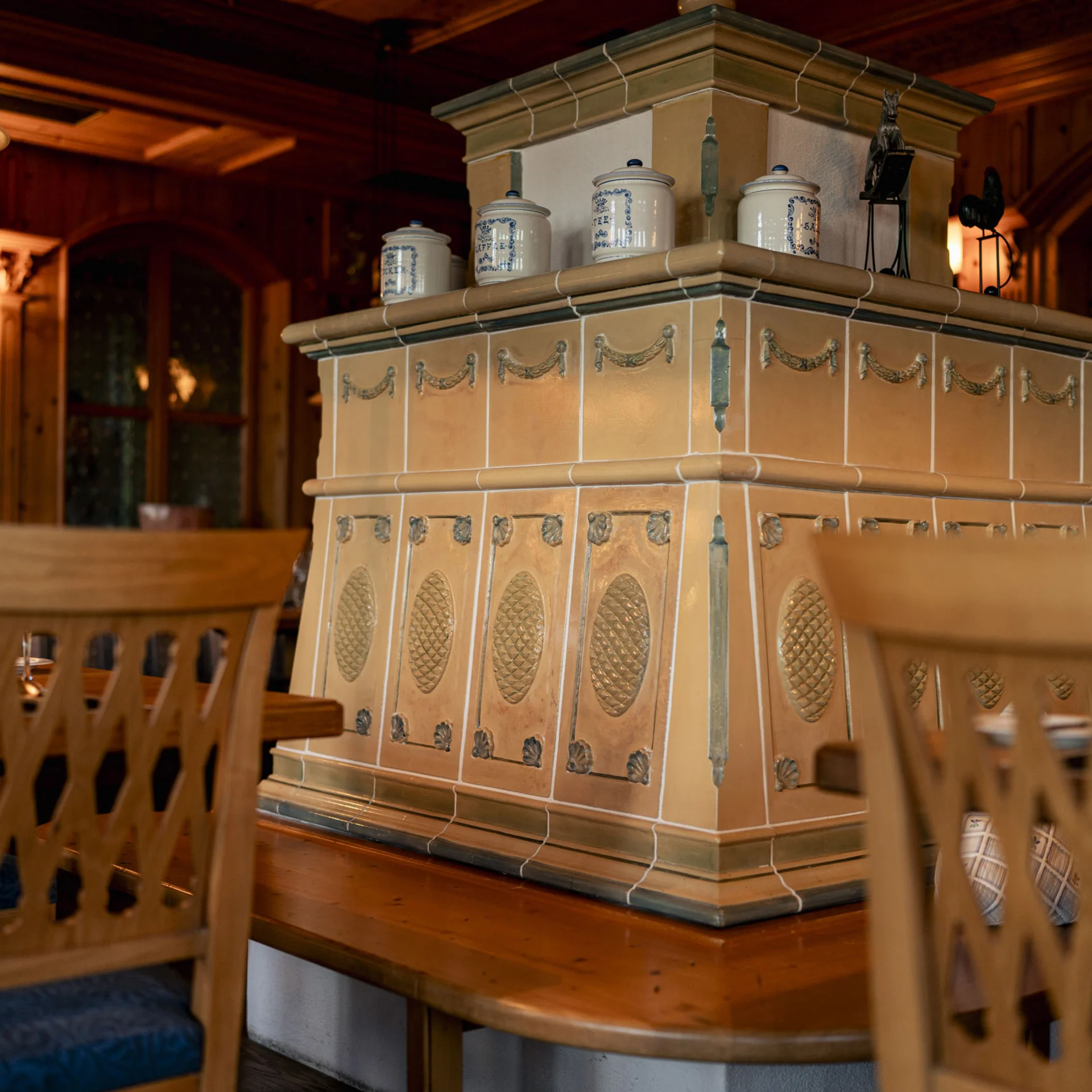 Traditioneller Kachelofen in gemütlichem, holzverkleidetem Restaurant