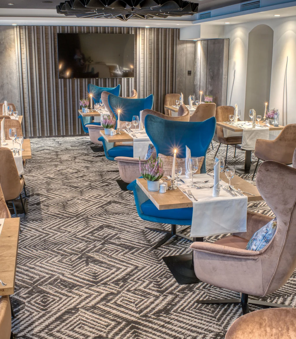 Elegantes Restaurant mit gedeckten Tischen und blauen sowie braunen Stühlen