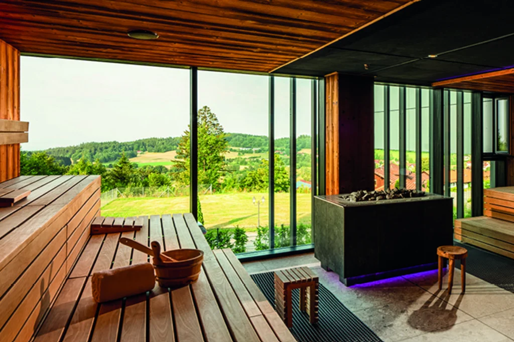 Für Feiern in kleiner und großer Runde Wellnessbereich mit Holzbänken, großen Fenstern und Blick auf die grüne Landschaft