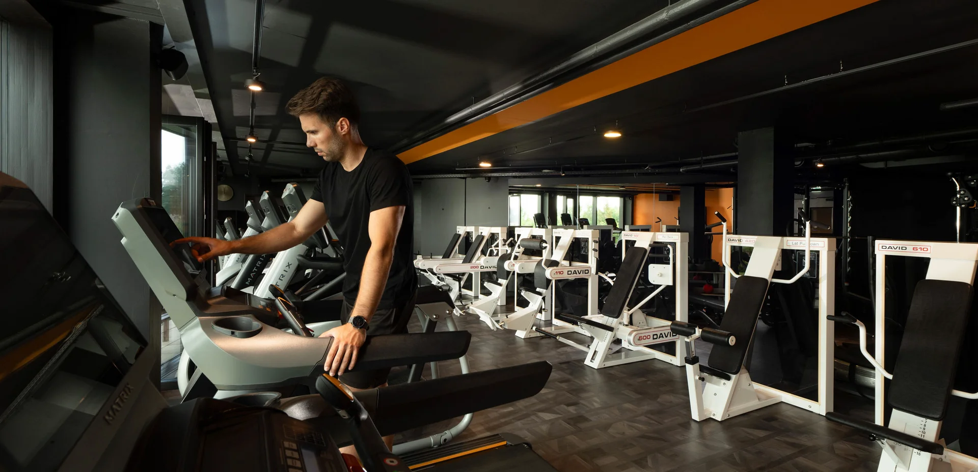 Mann bedient Laufband in einem modernen Fitnessstudio mit Trainingsgeräten