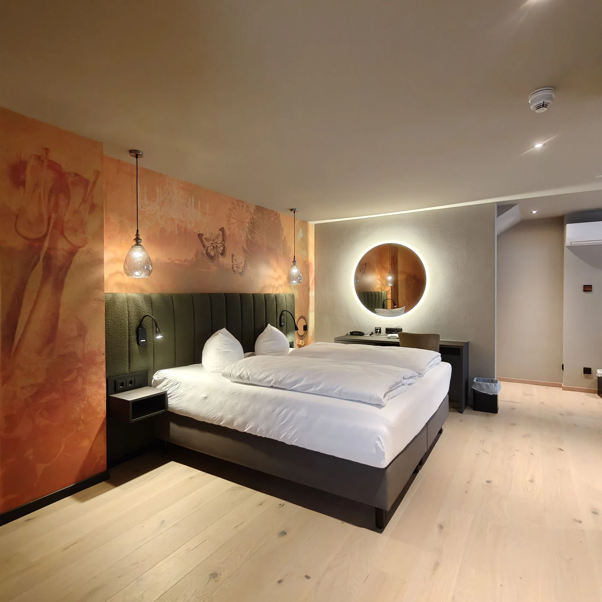 Modernes Hotelzimmer mit Doppelbett, Lampen und Wandkunst mit Tieren und Schmetterlingen