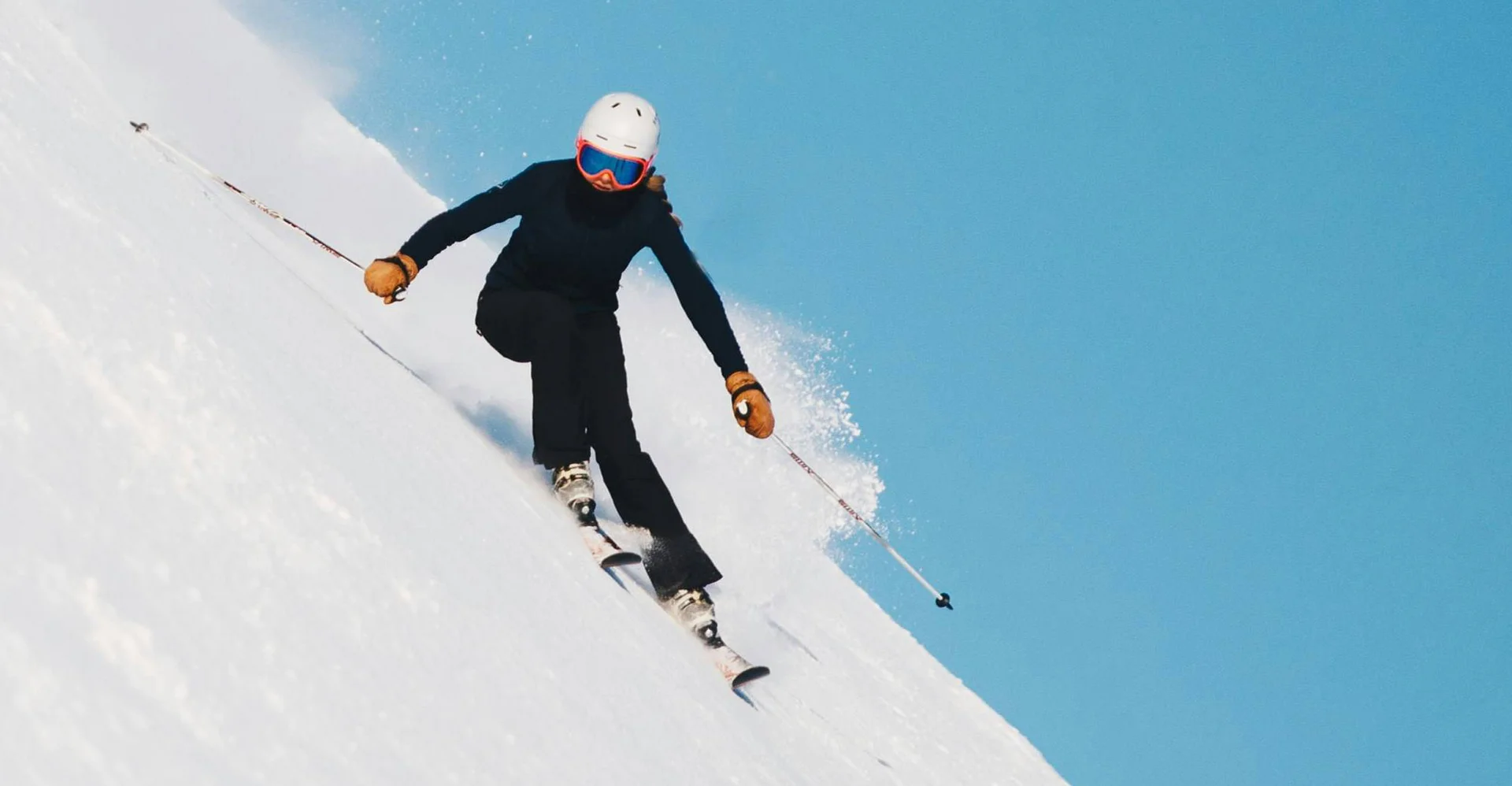 Skifahrer fährt schnell den schneebedeckten Hang bei blauem Himmel hinunter