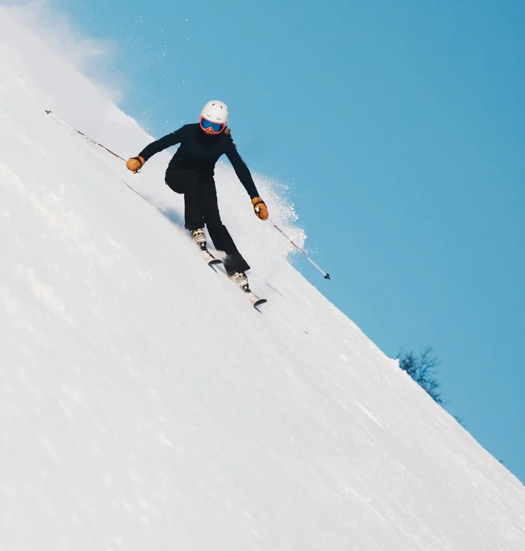 Skifahrer fährt schnell den schneebedeckten Hang bei blauem Himmel hinunter
