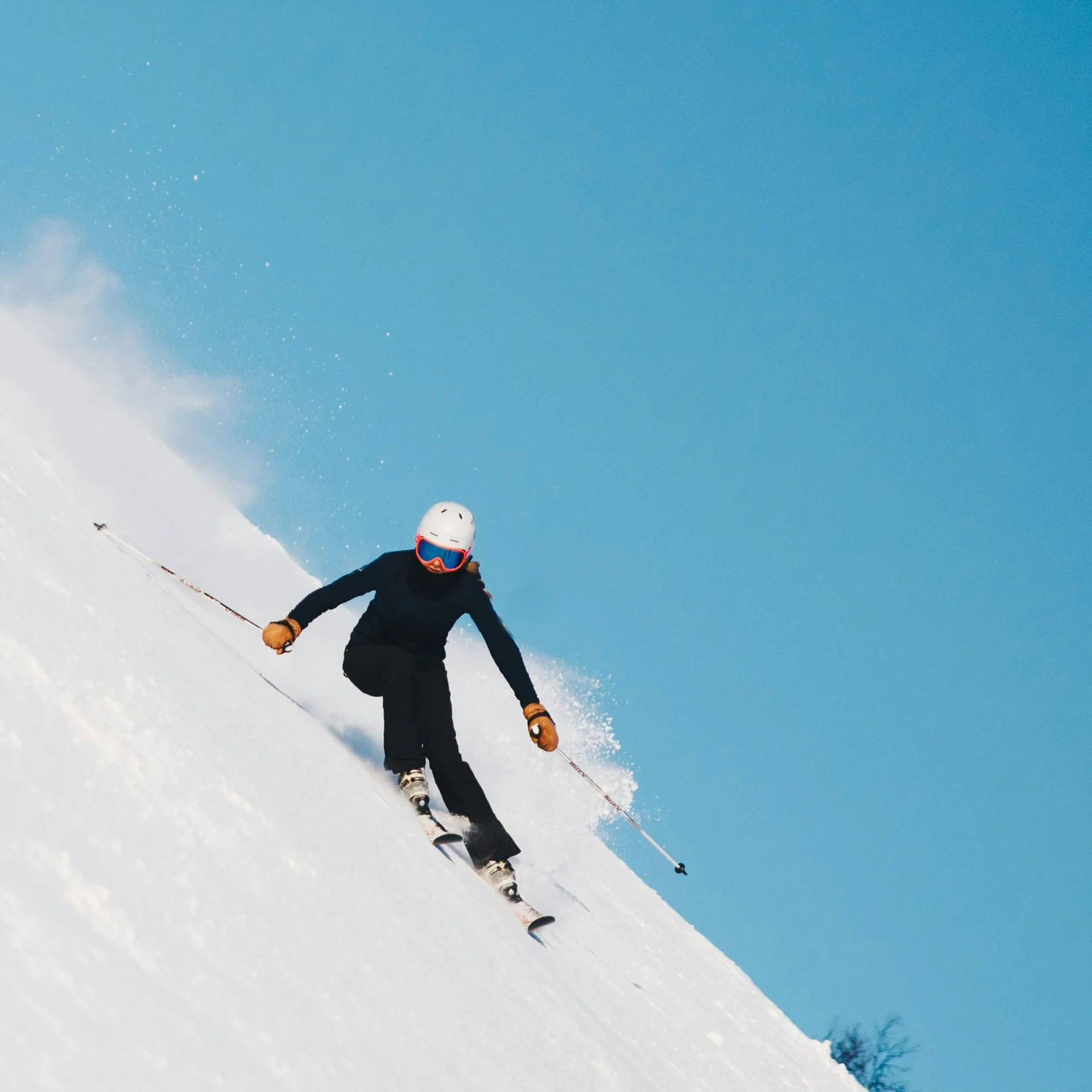 Skifahrer fährt schnell den schneebedeckten Hang bei blauem Himmel hinunter