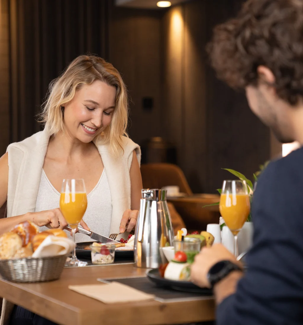 Die Adresse für Wellness in Bayern: Ihr Hotel in St. Englmar Paar genießt Frühstück mit Orangensaft und Gebäck im Restaurant