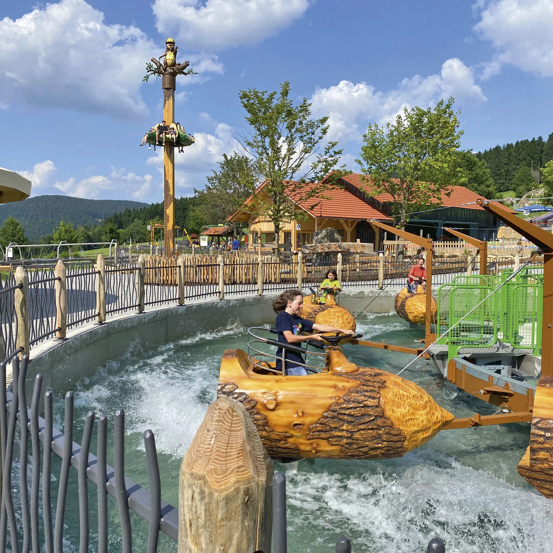 Kinder fahren in Holznuss-Boote auf einem Wasserkarussell im Freizeitpark