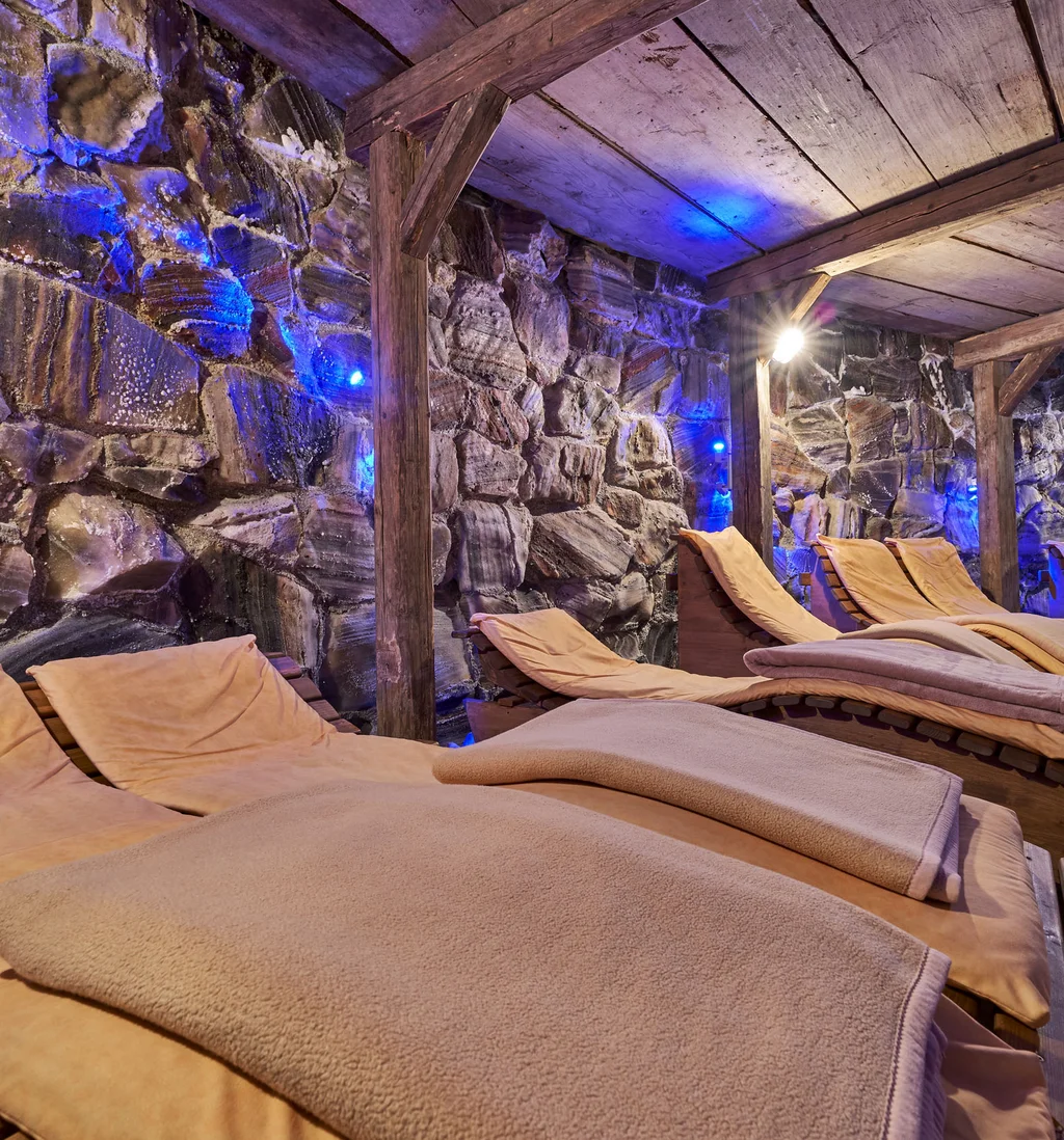 Ruheraum mit Liegen vor einer beleuchteten Natursteinwand