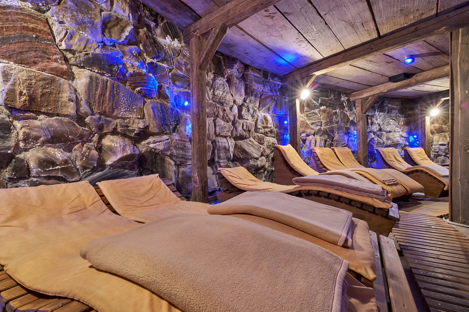 Ruheraum mit Liegen vor einer beleuchteten Natursteinwand