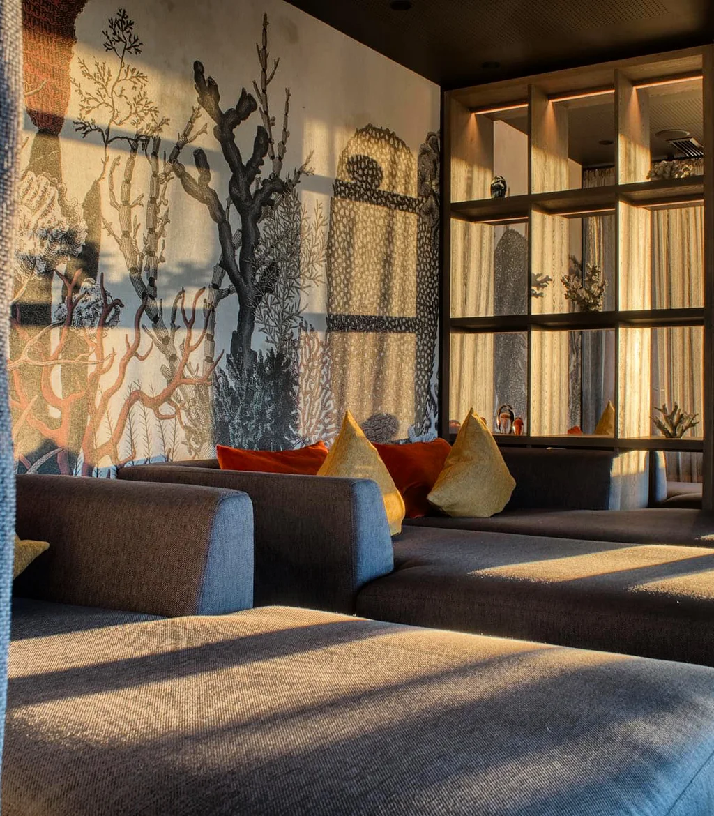 Gemütliche Lounge mit dunklen Sofas und gemusterter Wandbeleuchtung