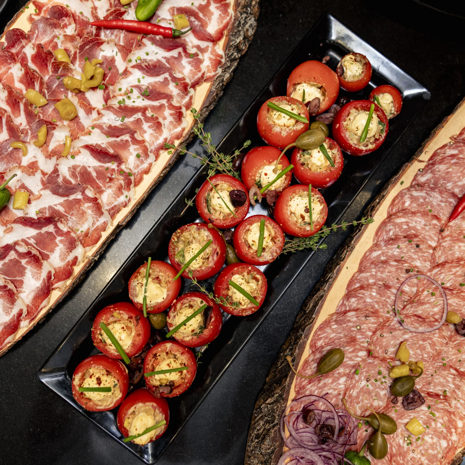 Teller mit verschiedenen Wurstscheiben und gefüllten Tomaten als Vorspeise