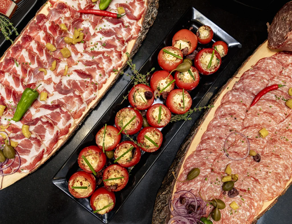 Teller mit verschiedenen Wurstscheiben und gefüllten Tomaten als Vorspeise