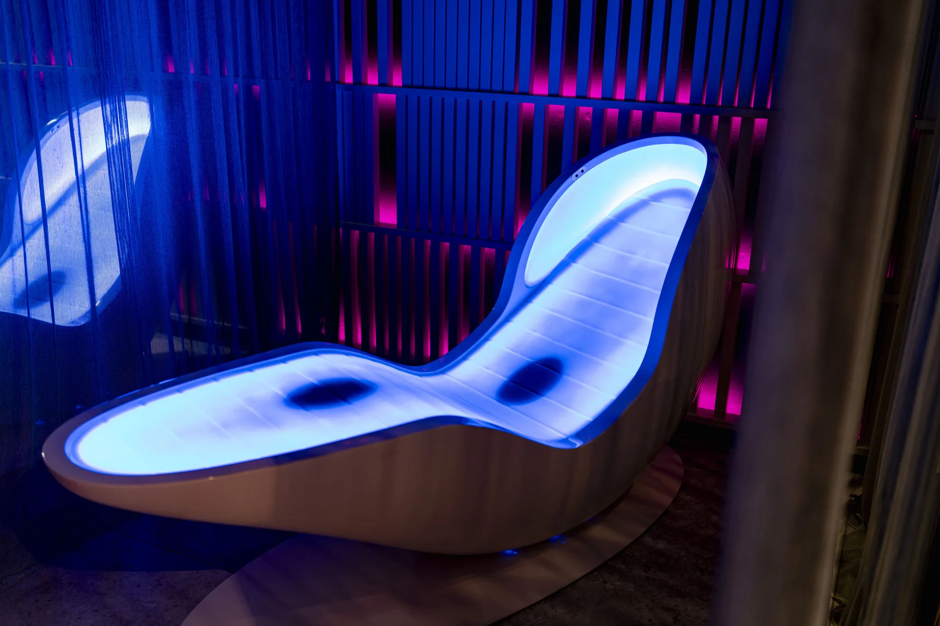 Modernes beleuchtetes Lounge-Sofa mit blauem und pinkem Licht in einem Raum