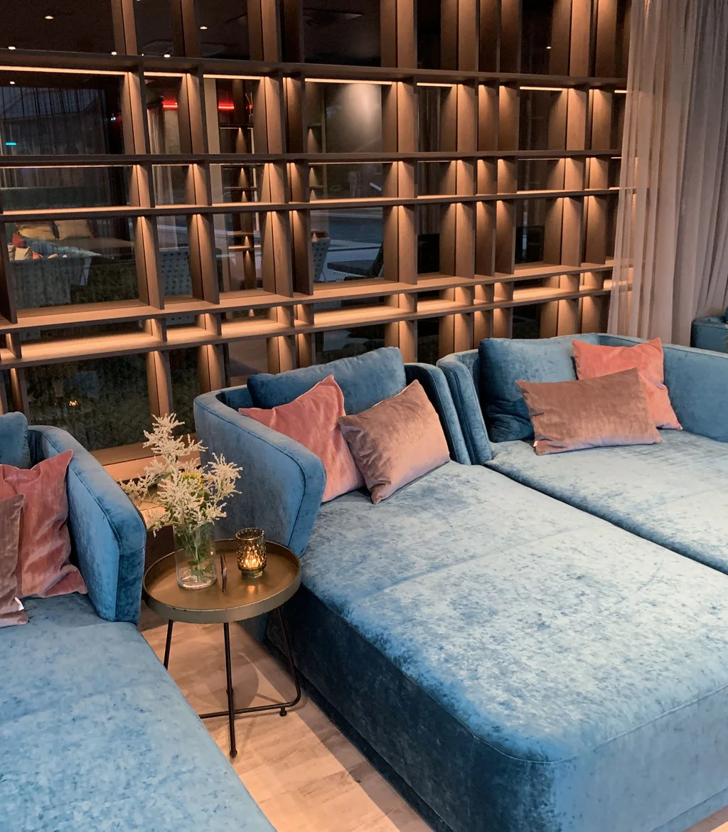 Gemütliche blaue Sofas mit Kissen und Beistelltischen in modernem Wohnzimmer