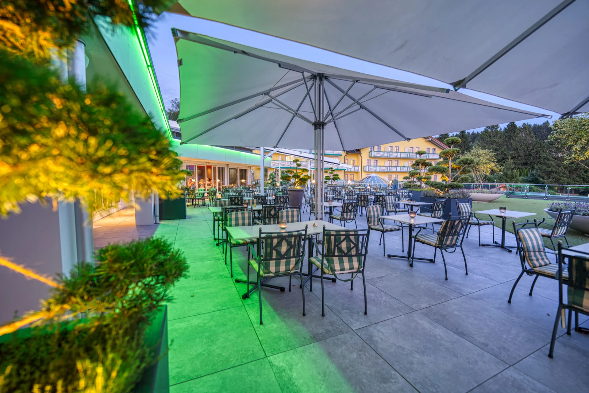 Freiluftrestaurant mit Sonnenschirmen und Stühlen in einem Gartenbereich