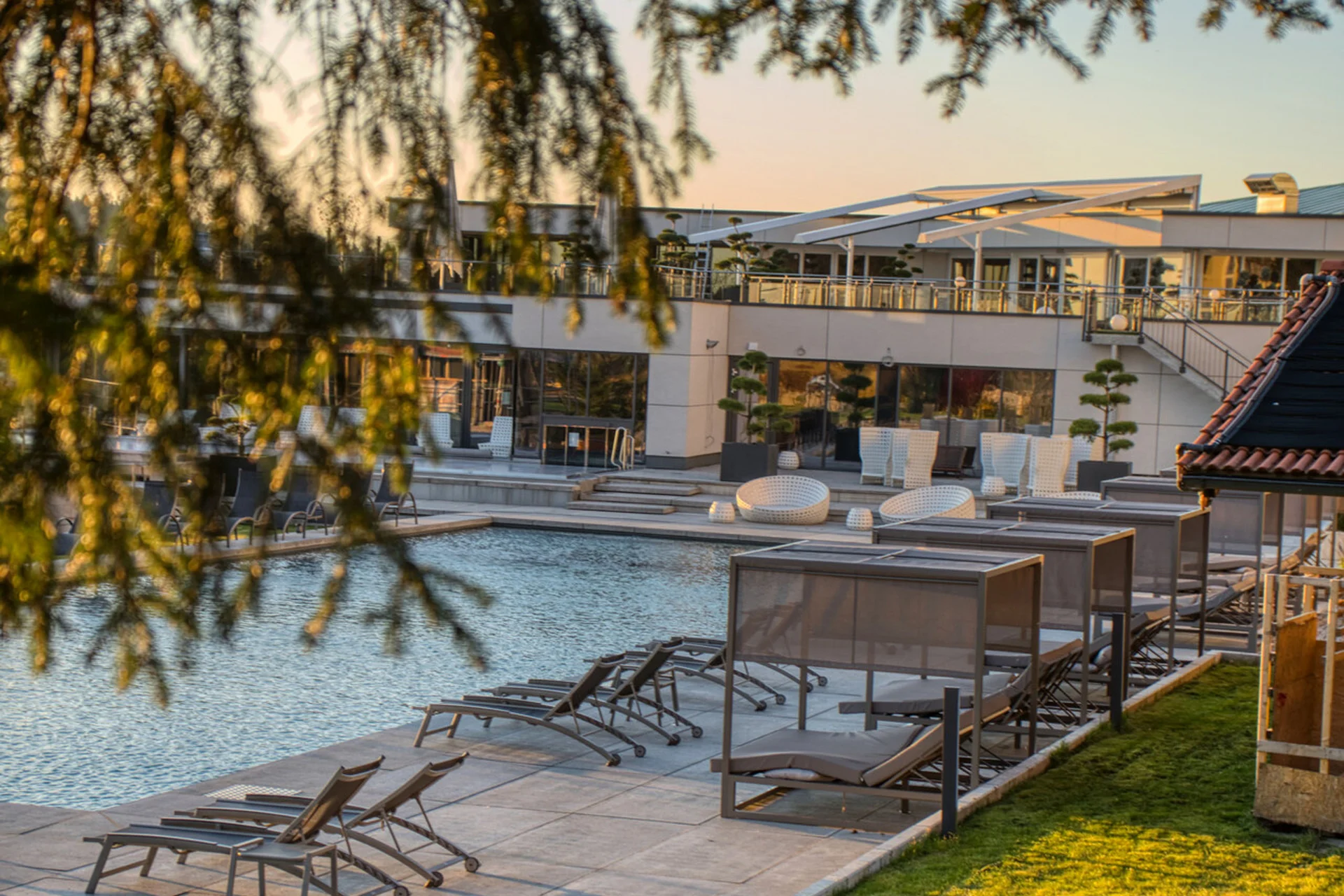 Moderner Poolbereich mit Sonnenliegen und Lounge-Möbeln bei Sonnenuntergang