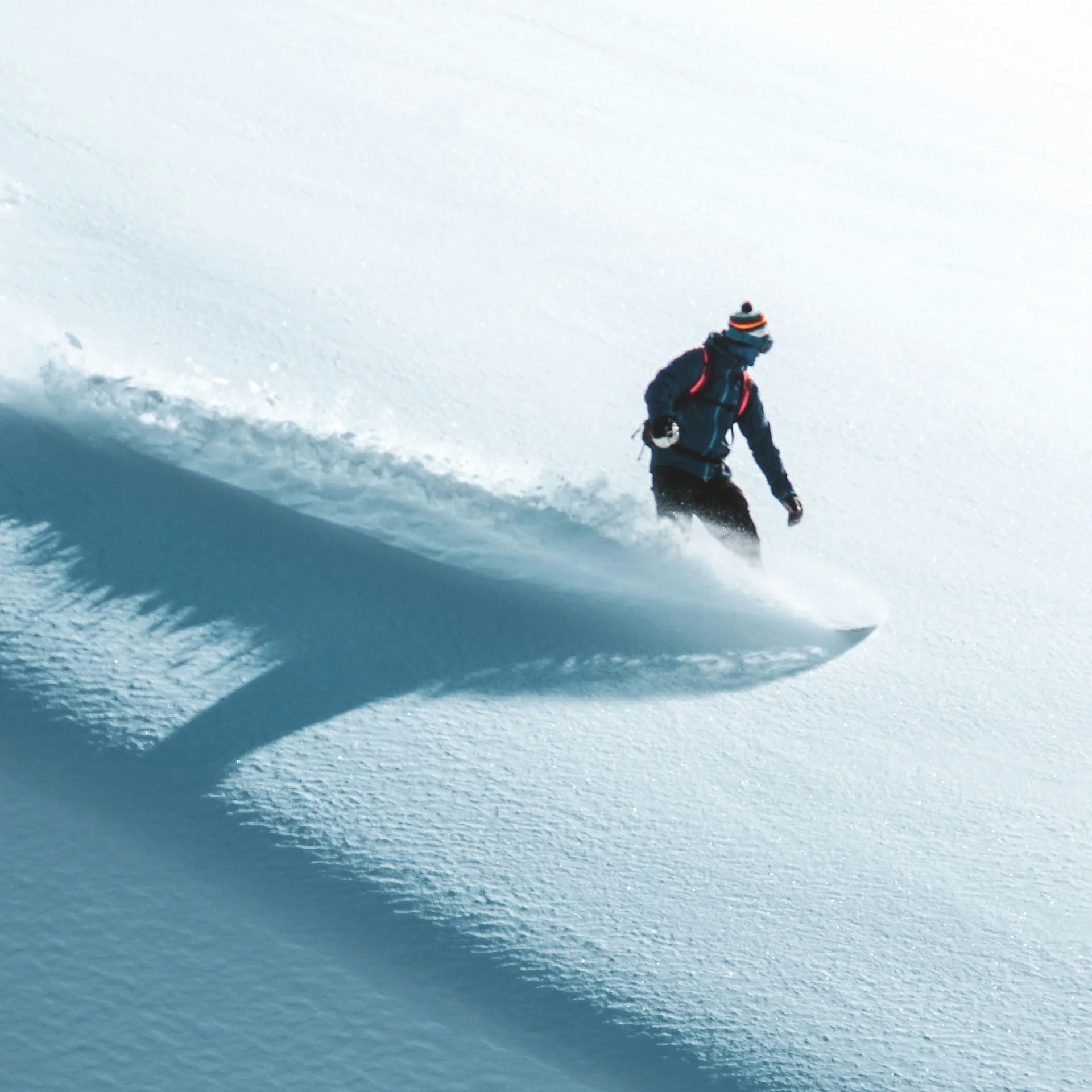 Person beim Snowboarden auf verschneiter Piste mit Schatten auf Schnee