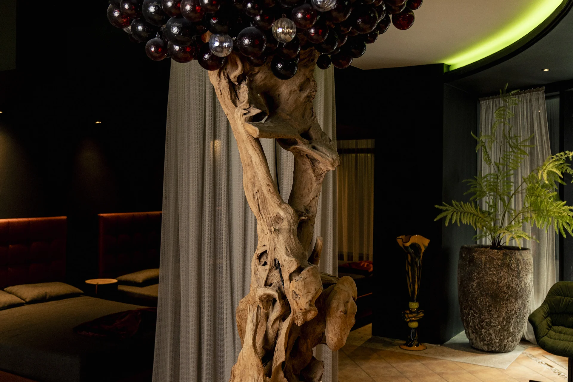 Kunstinstallation mit Holzstamm und Glaskugeln als Baum im Innenraum