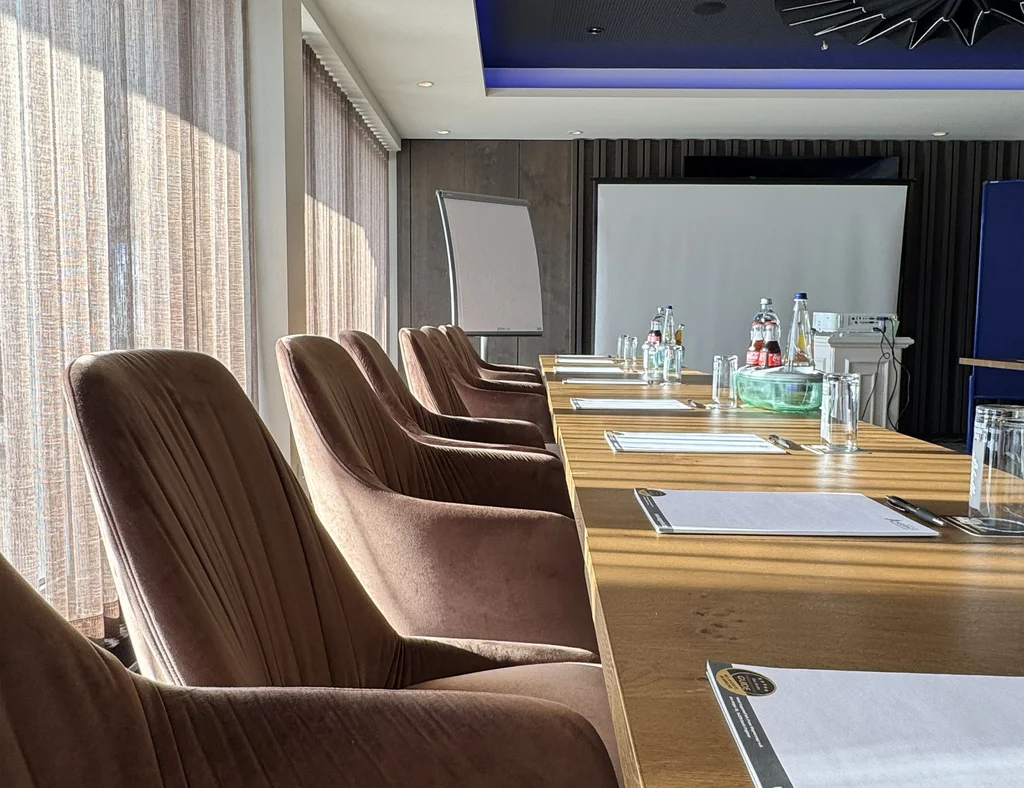 Konferenzraum mit Tischen, Stühlen und Flipchart bei Tageslicht