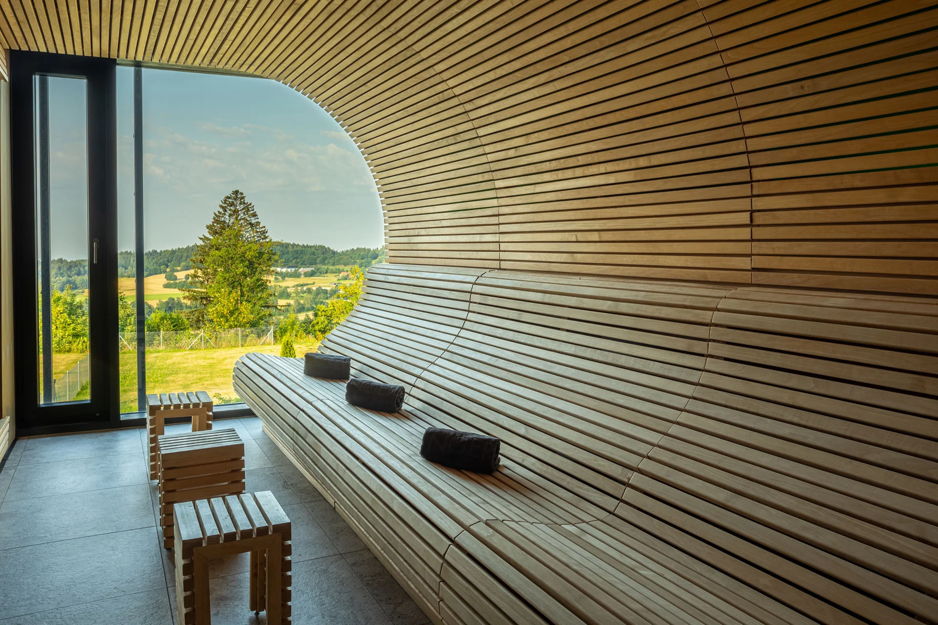 Holzsauna mit Sitzbänken und Ausblick auf grüne Landschaft