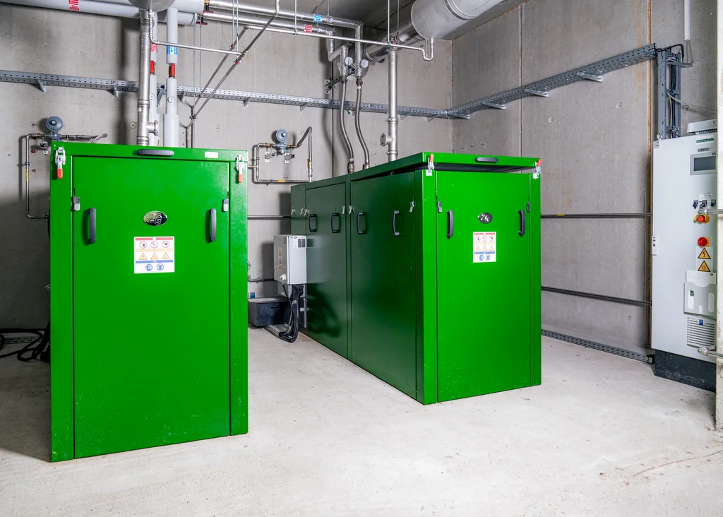 Grüne Heizungsanlage in einem Betonraum mit Rohren und Schaltern