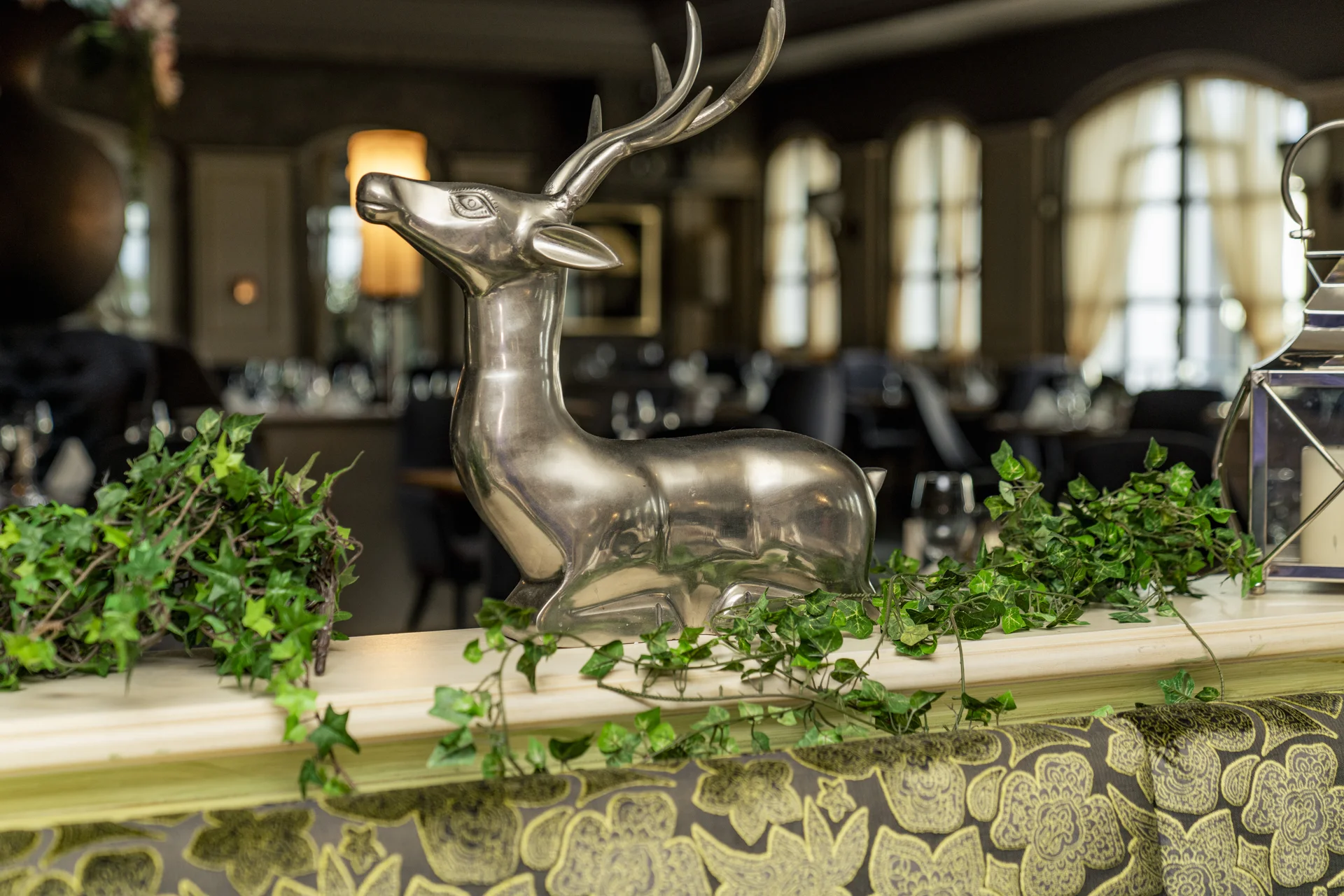 Silberne Hirschskulptur in eleganter Restaurantumgebung mit Pflanzen