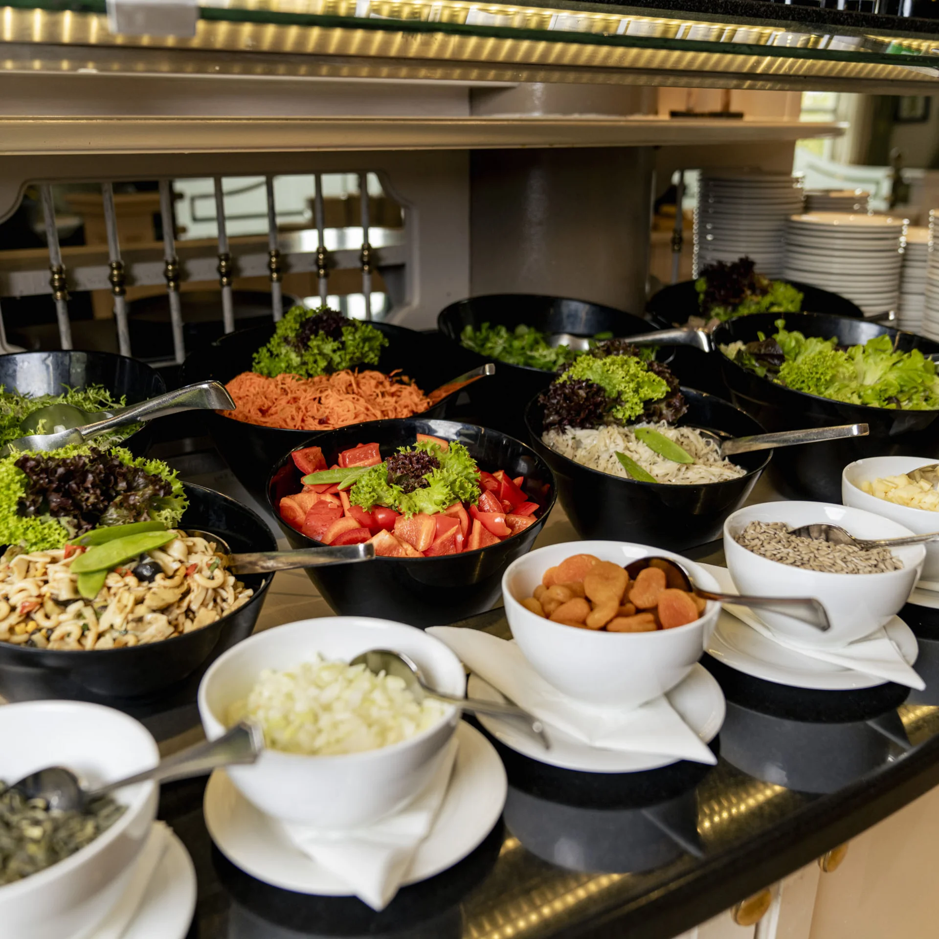 Buffet mit verschiedenen frischen Salaten und Zutaten in Schalen auf einer Theke