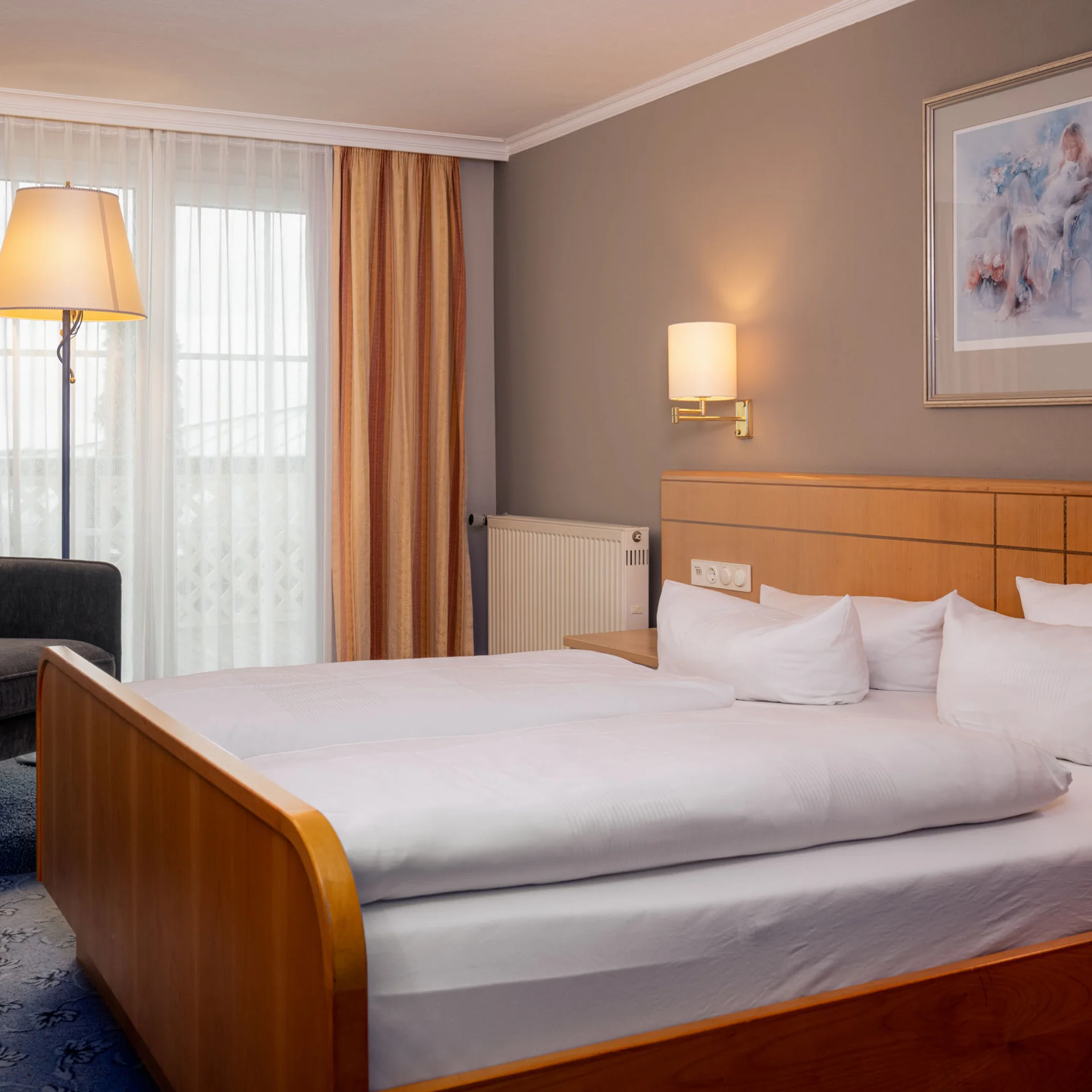 Gemütliches Hotelzimmer mit Doppelbett, Sessel und Beleuchtung