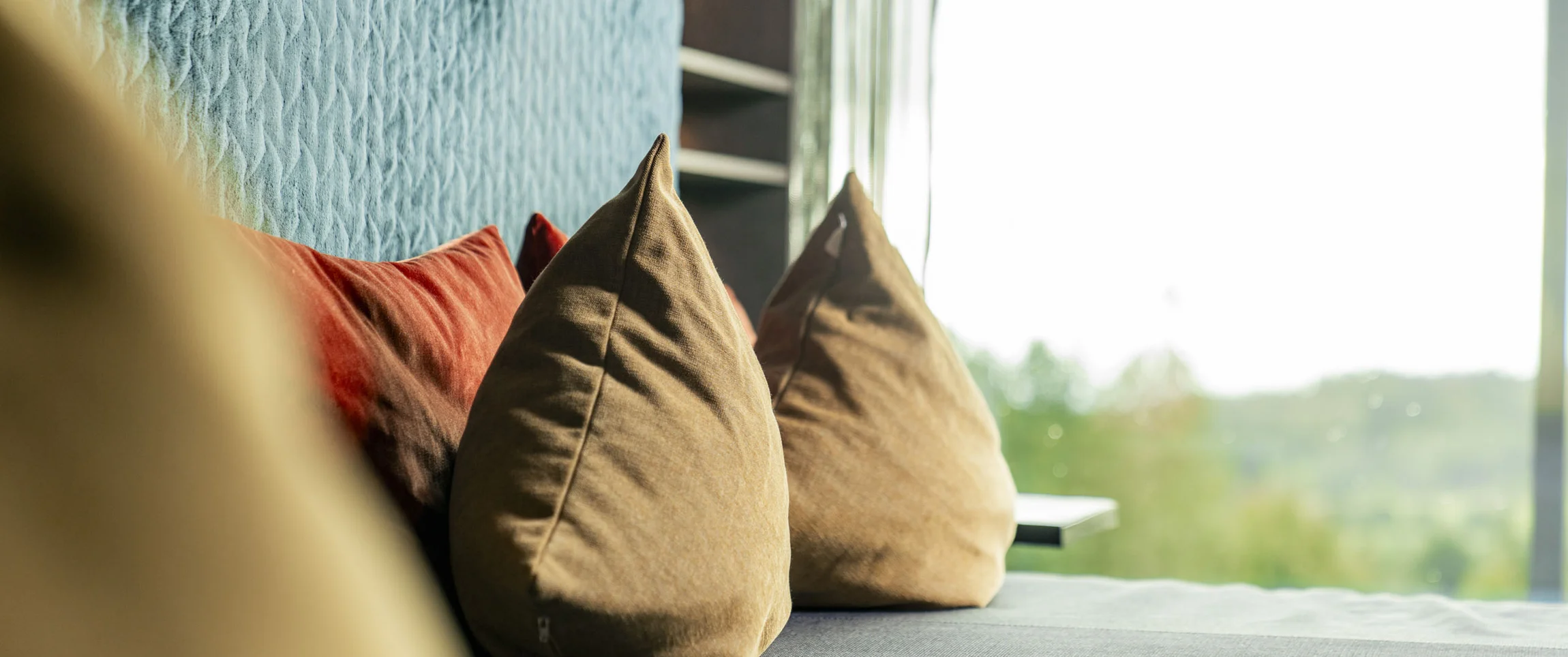 Nahaufnahme von braunen und roten Kissen an einem blauen gepolsterten Sofa