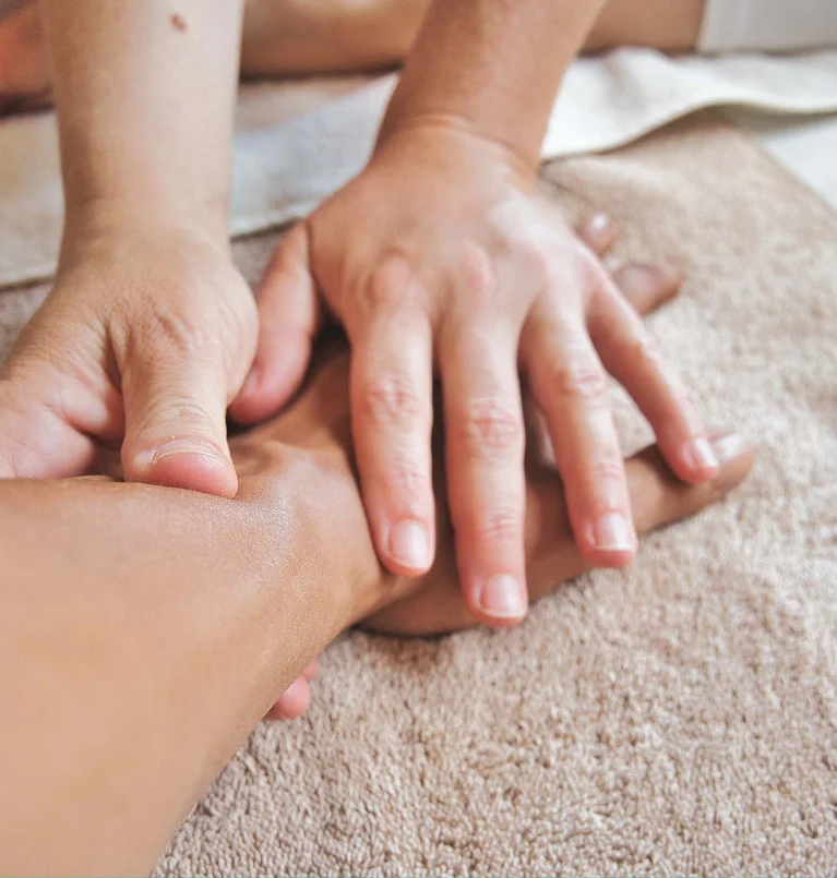 Hände, die eine Rückenmassage auf einem Handtuch geben