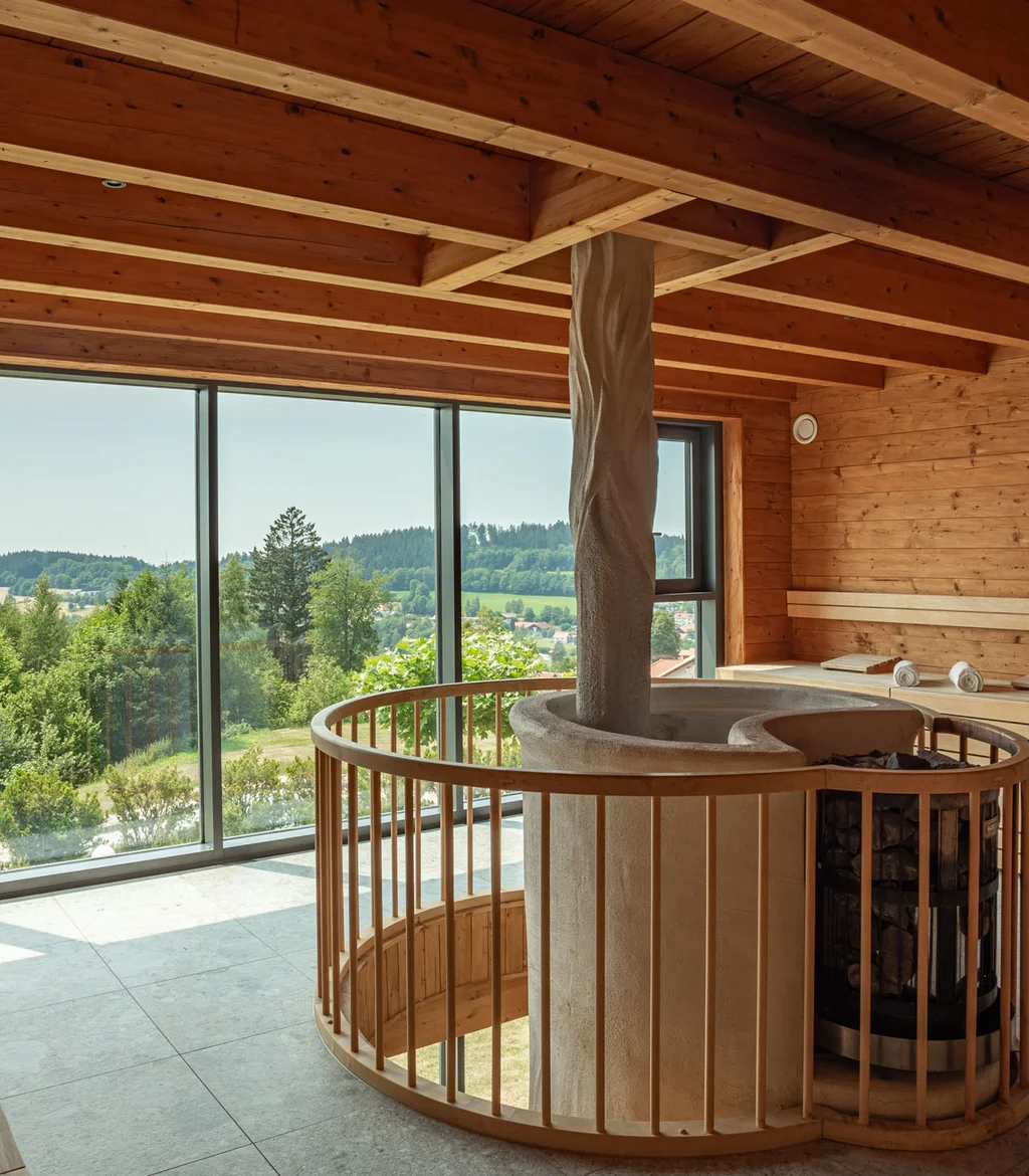 Innenraum einer Sauna mit Holzverkleidung und großer Fensterfront mit Blick ins Grüne