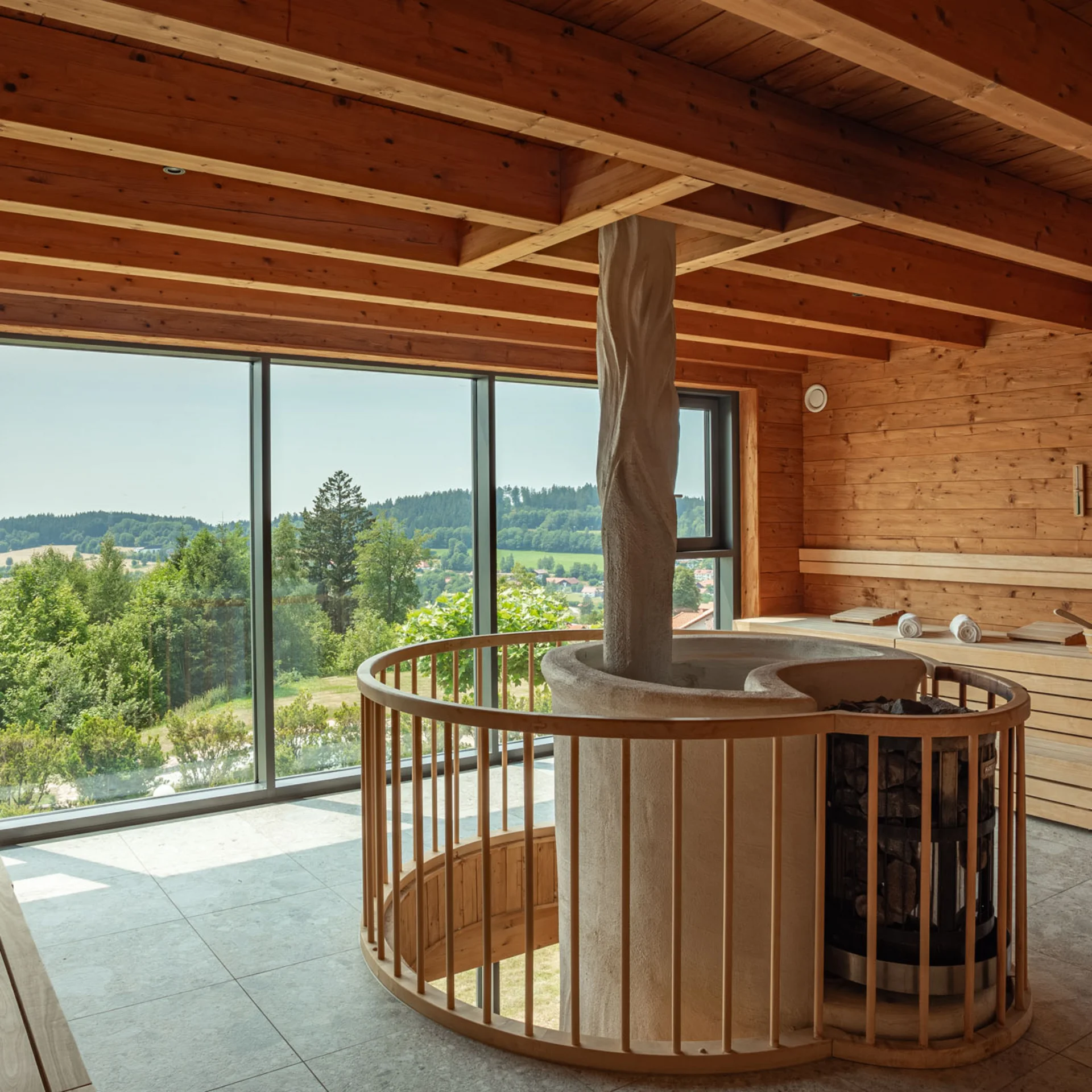 Innenraum einer Sauna mit Holzverkleidung und großer Fensterfront mit Blick ins Grüne