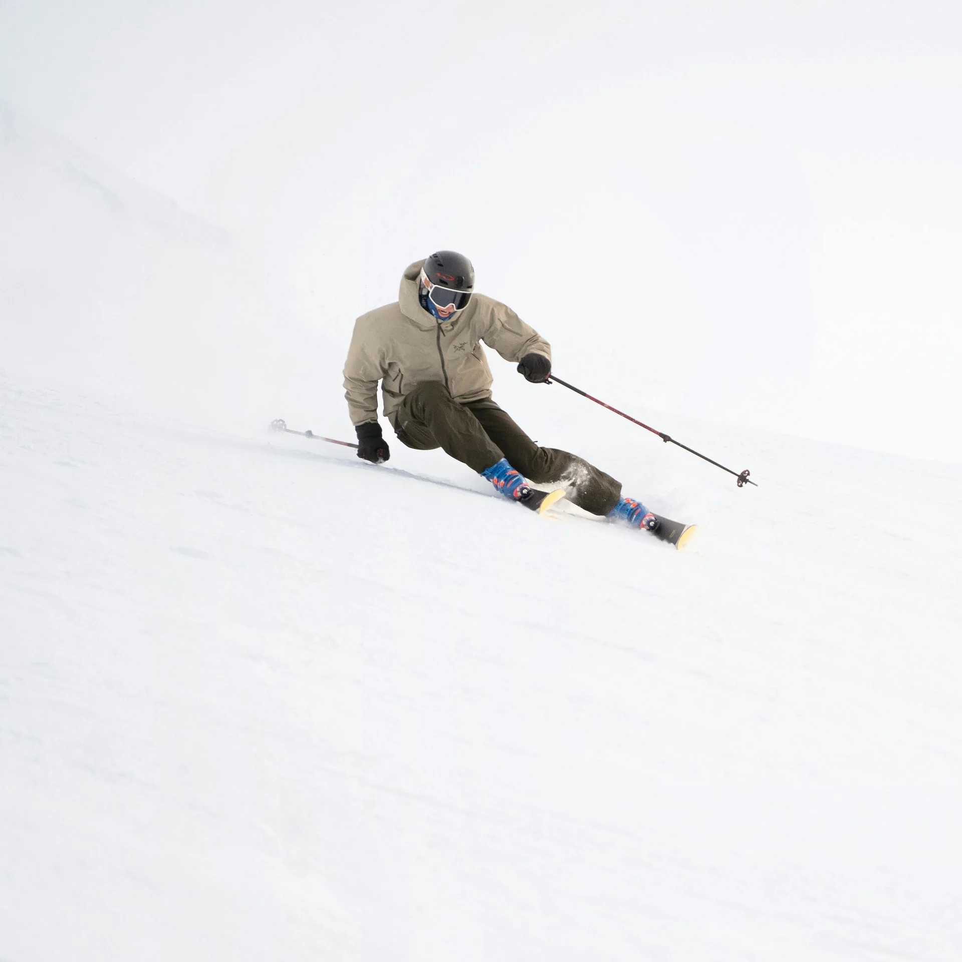 Skifahrer in brauner Jacke fährt auf verschneiter Piste bei Nebel