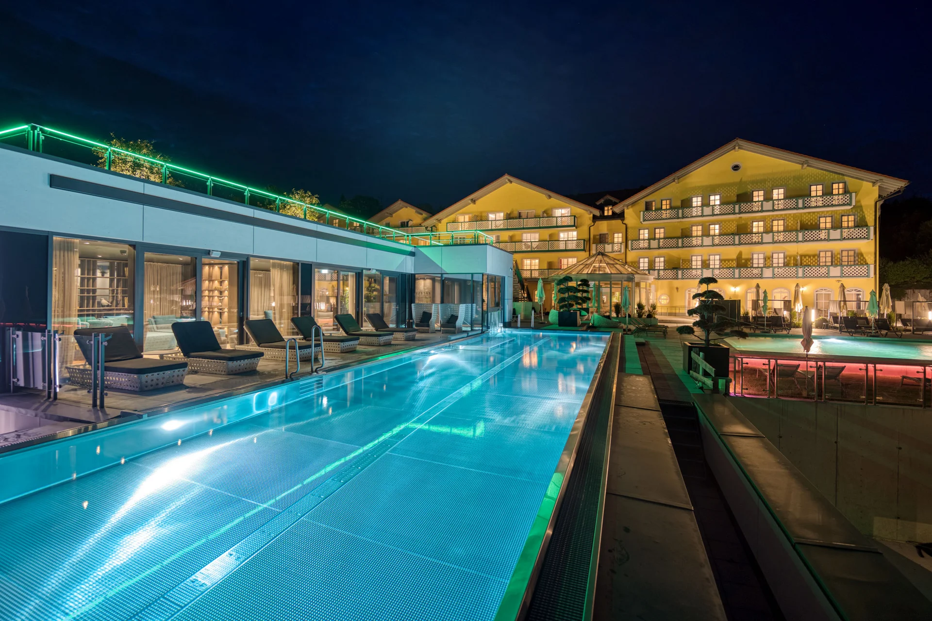 Beleuchtetes Hotel mit Poolbereich bei Nacht
