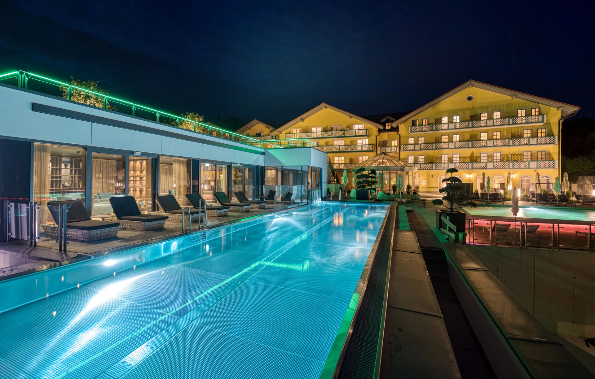 Beleuchtetes Hotel mit Poolbereich bei Nacht