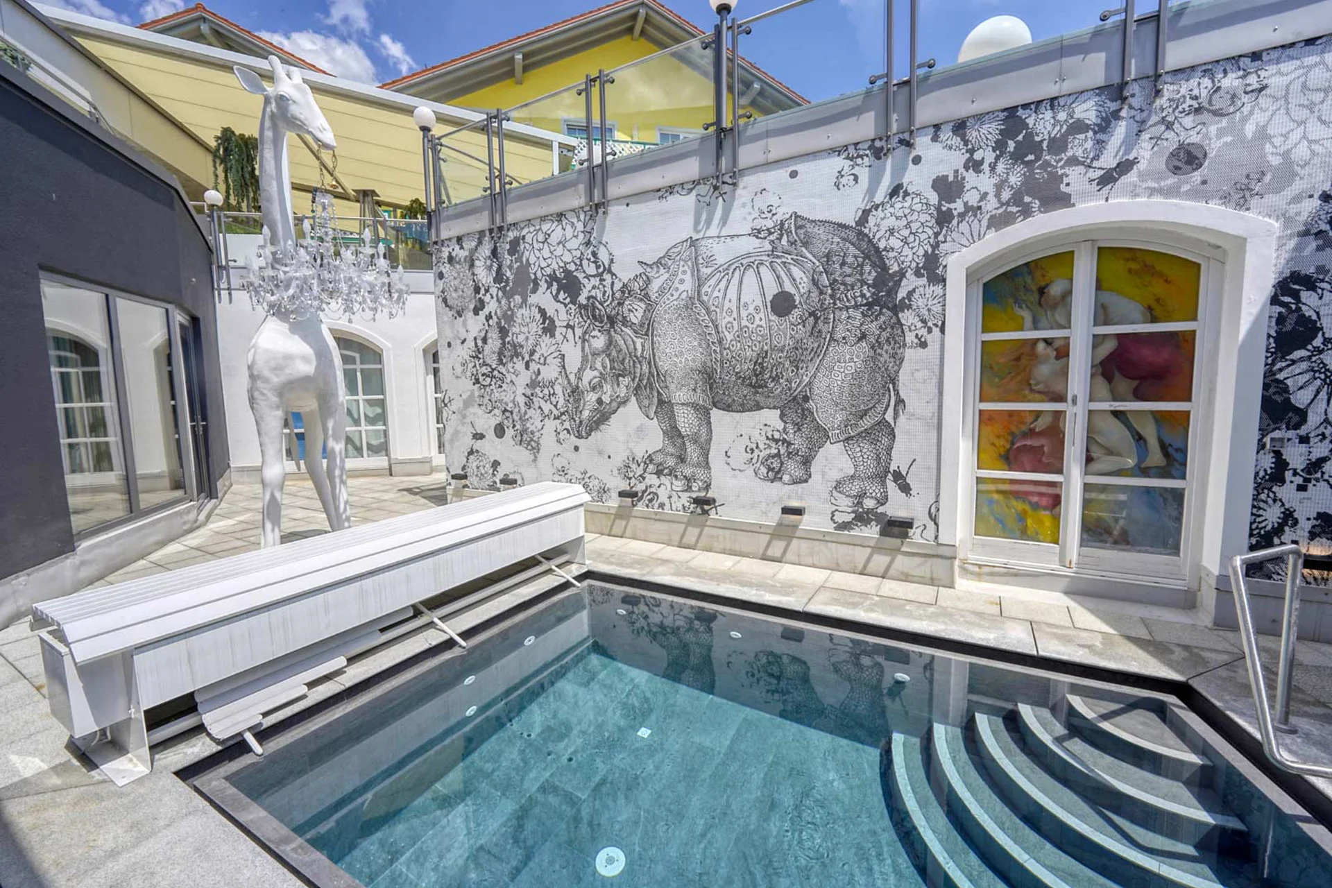 Moderner Innenhof mit Pool, weißer Giraffen-Skulptur und Kunst an der Wand